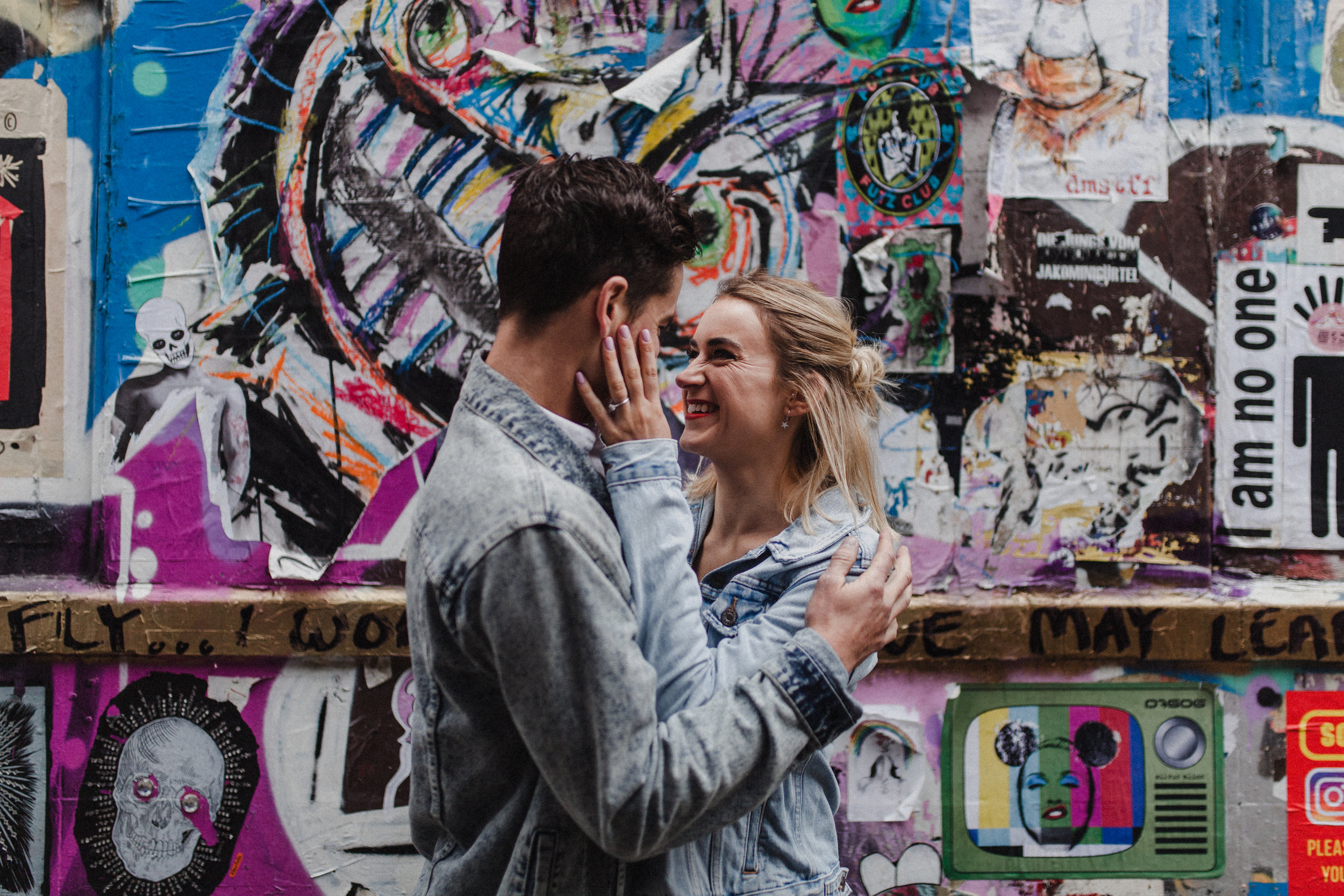 Couple embrace showing engagement ring in Brick Lane, London.