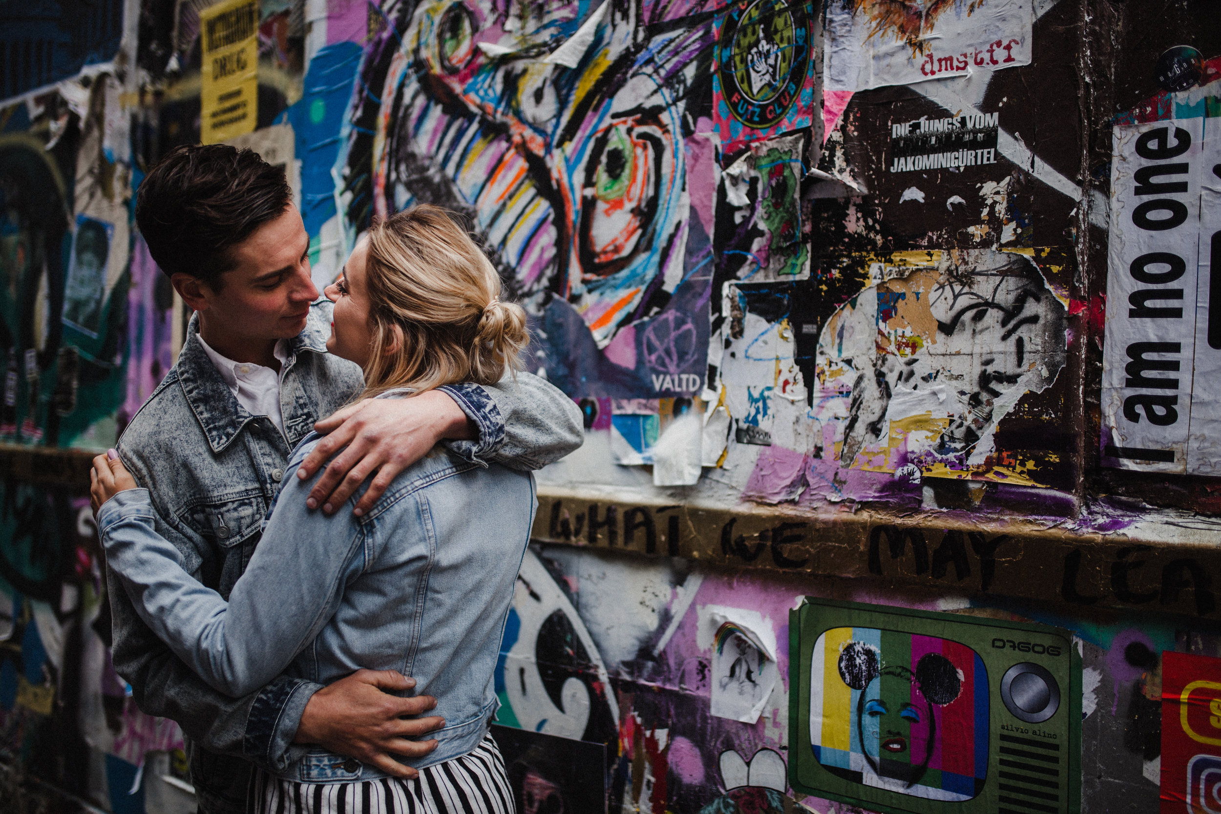 Couple embrace during their couple shoot in Brick Lane, featuring a colourful graffiti wall as a backdrop.