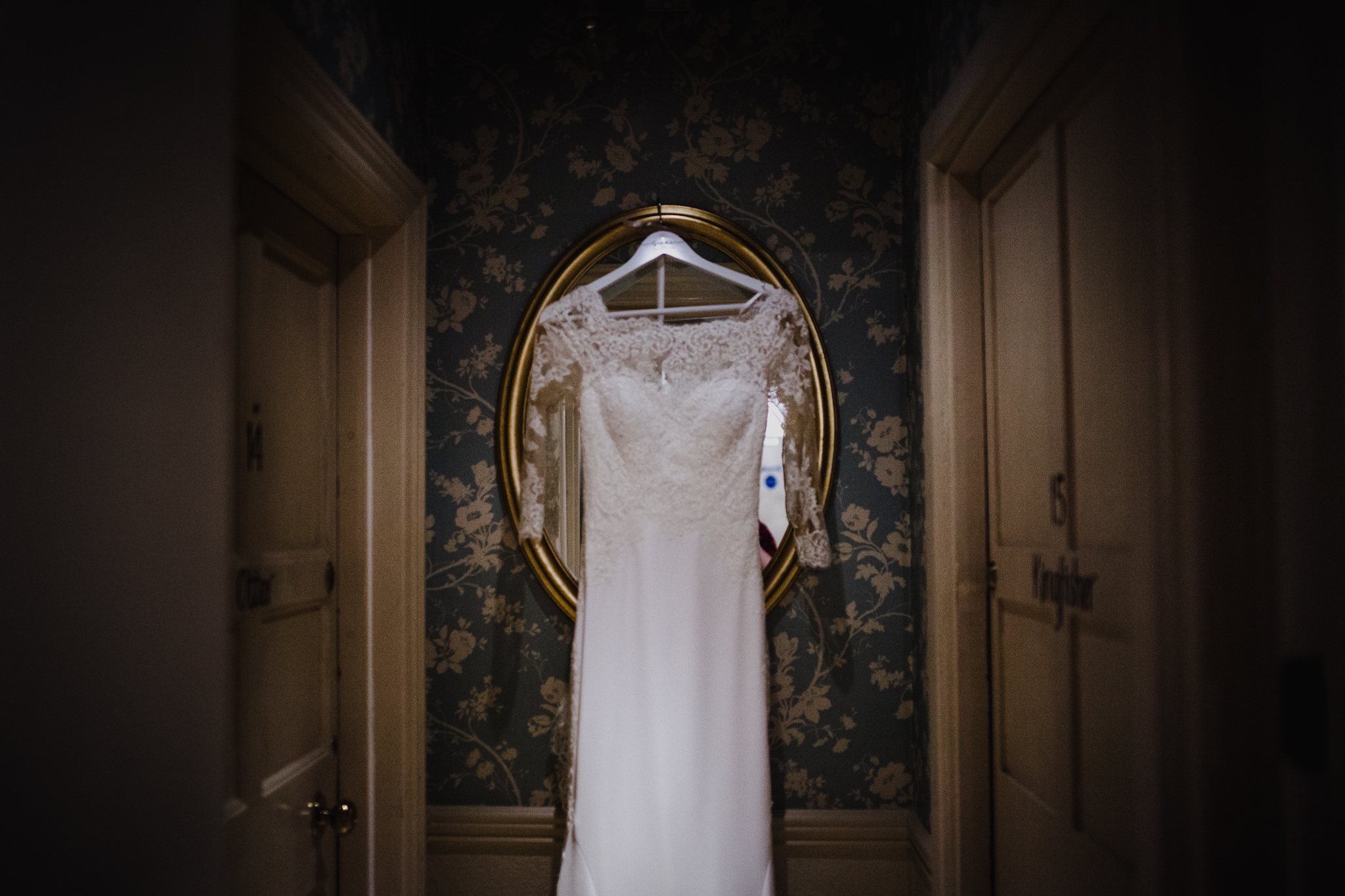 Wedding dress hanging on mirror with patterned wallpaper