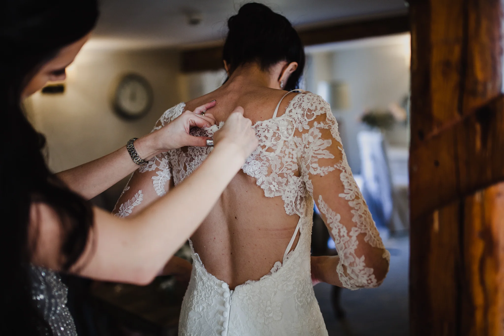 Bridesmaid doing up the brides dress in a hotel room