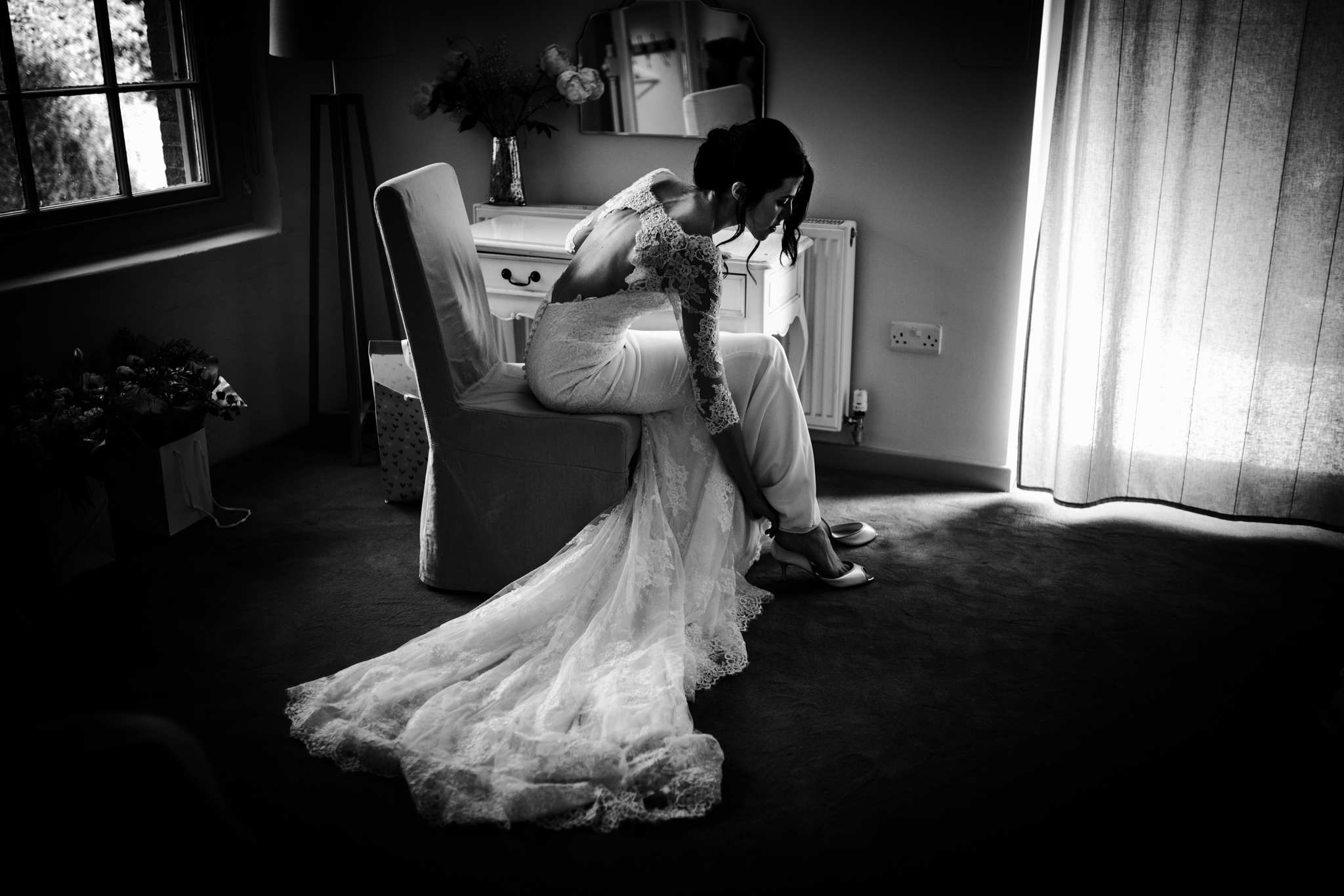Bride putting her shoes on in a tidy hotel room