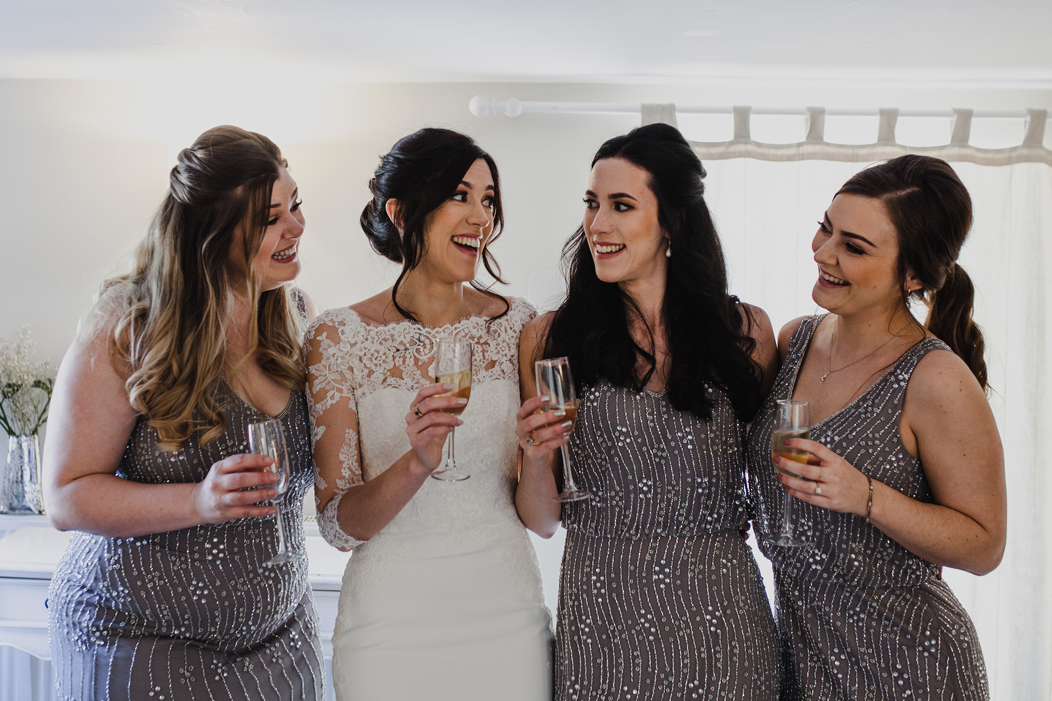 Bride and bridesmaids toasting and being happy in a hotel room