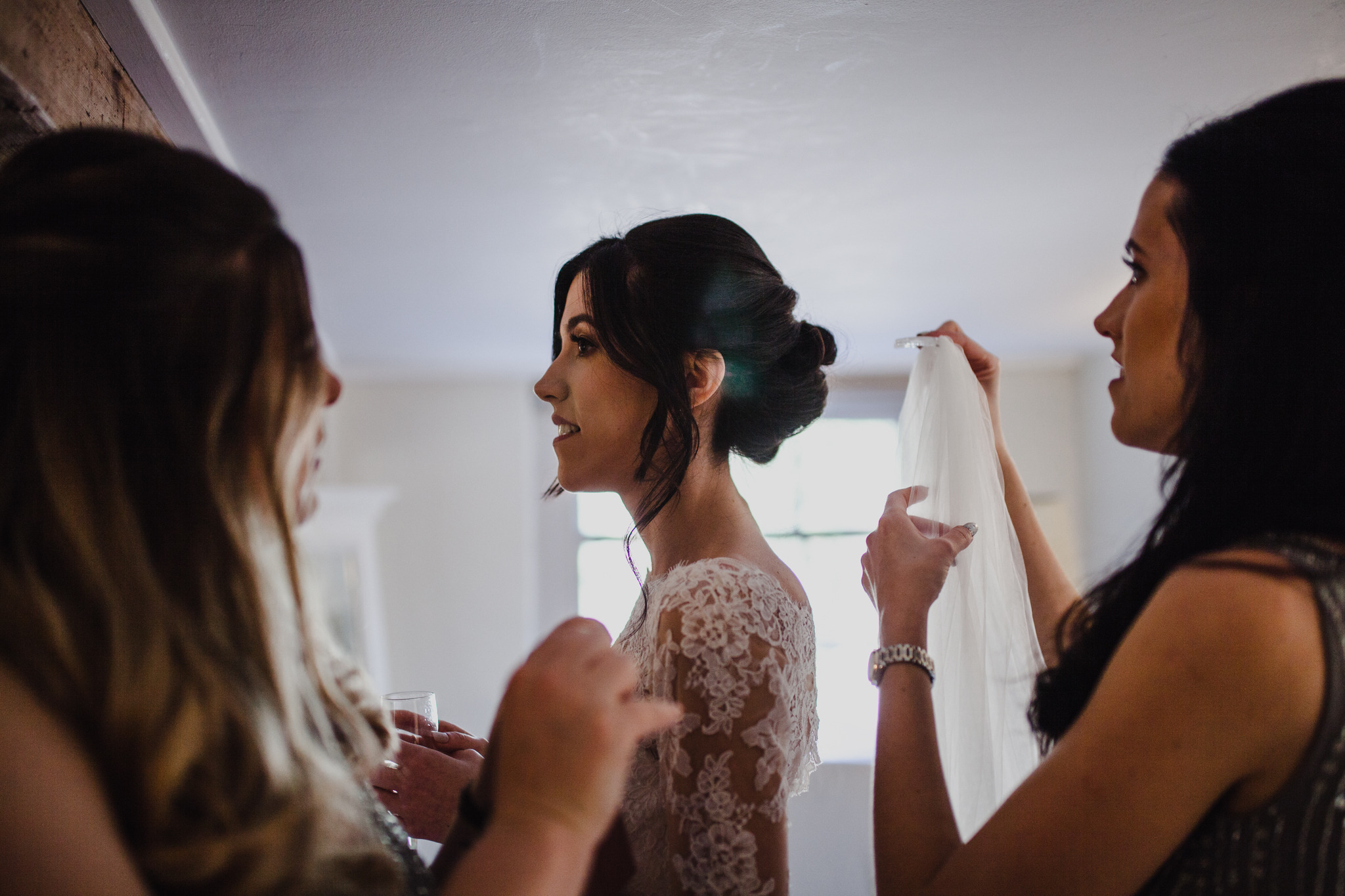 Maid of honor putting on the brides veil in hotel room