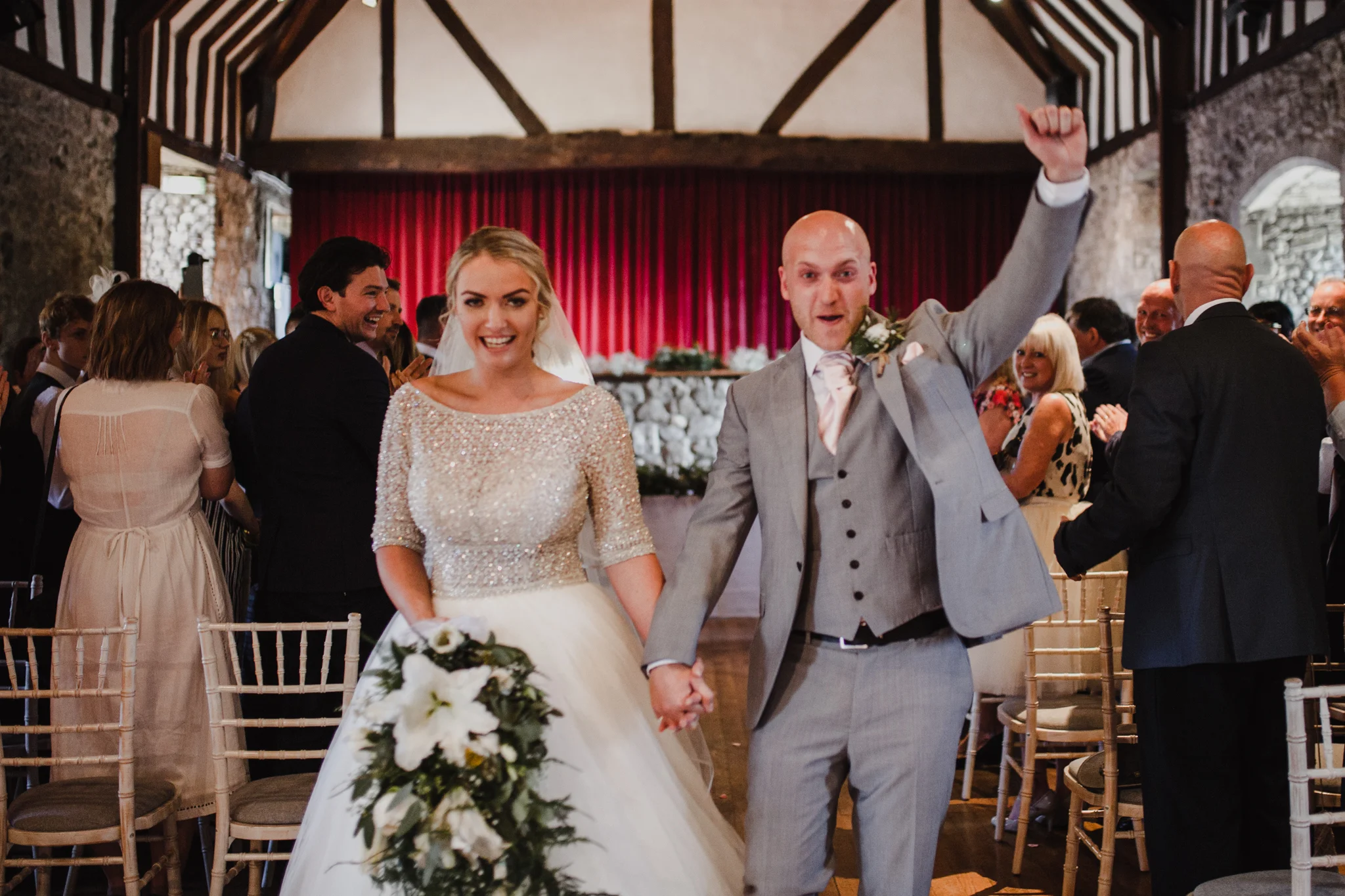 Very happy bride and groom celebrating as they walk down the aisle together