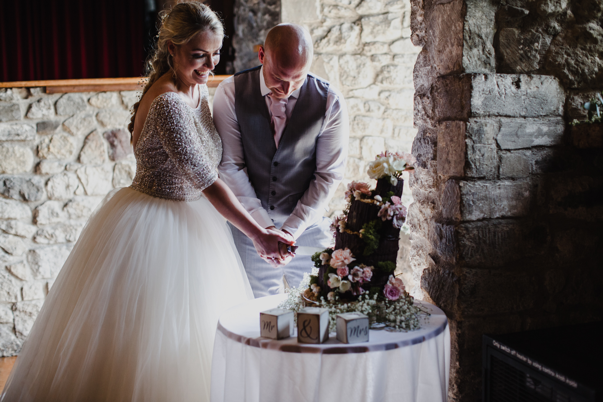 bride and groom cutting cake in window light