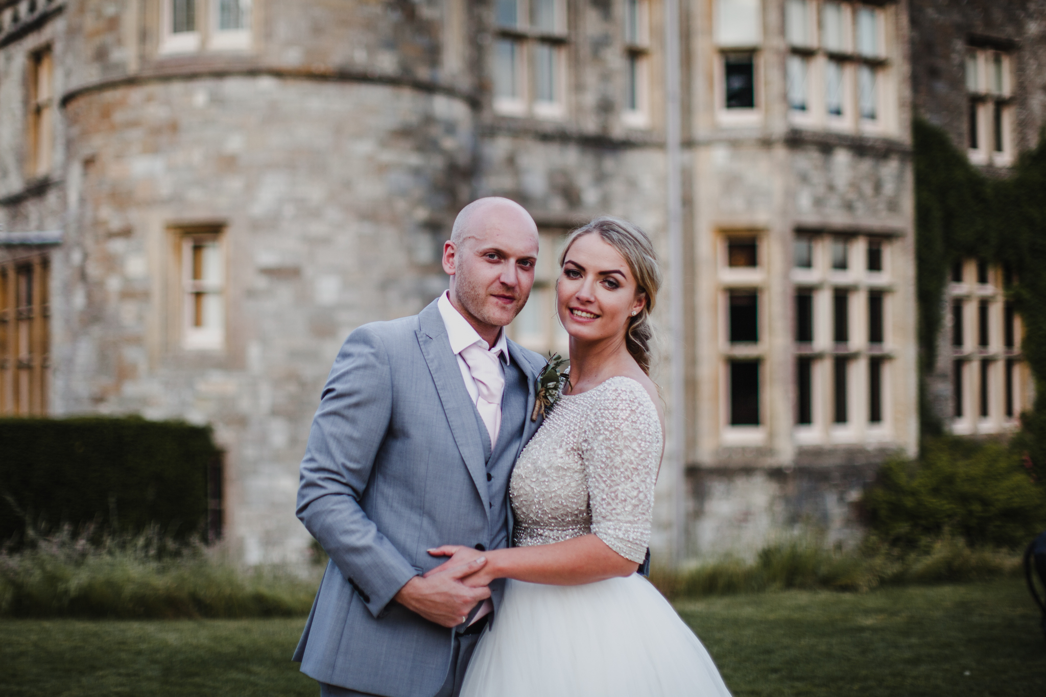 Bride and groom smiling in front of a castle