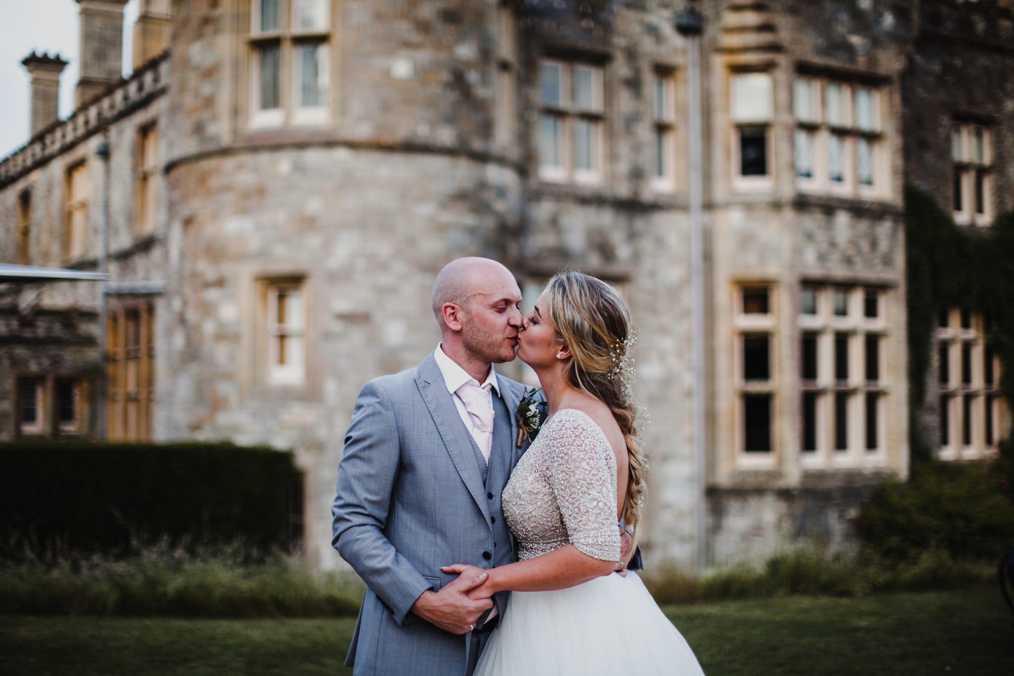 Bride and groom kissing in front of a stone english castle