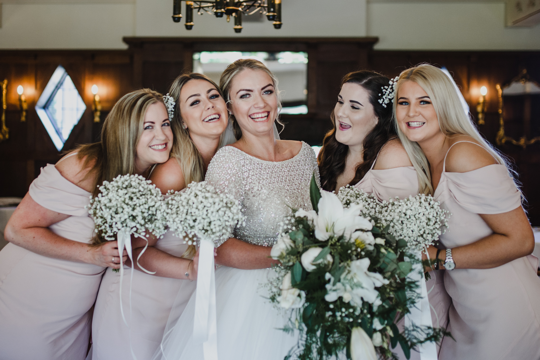 bride and her bridesmaids laughing together before a wedding