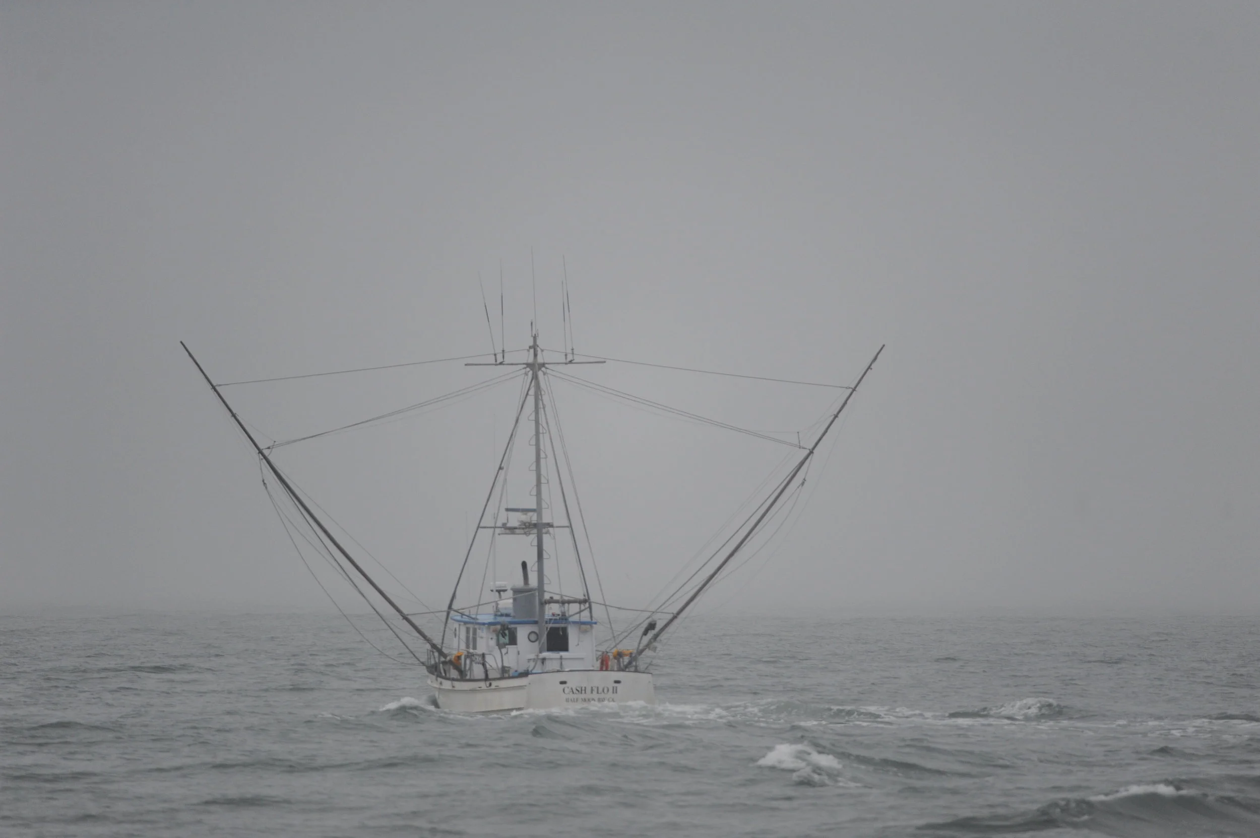 A fishing boat heading out into the fog.