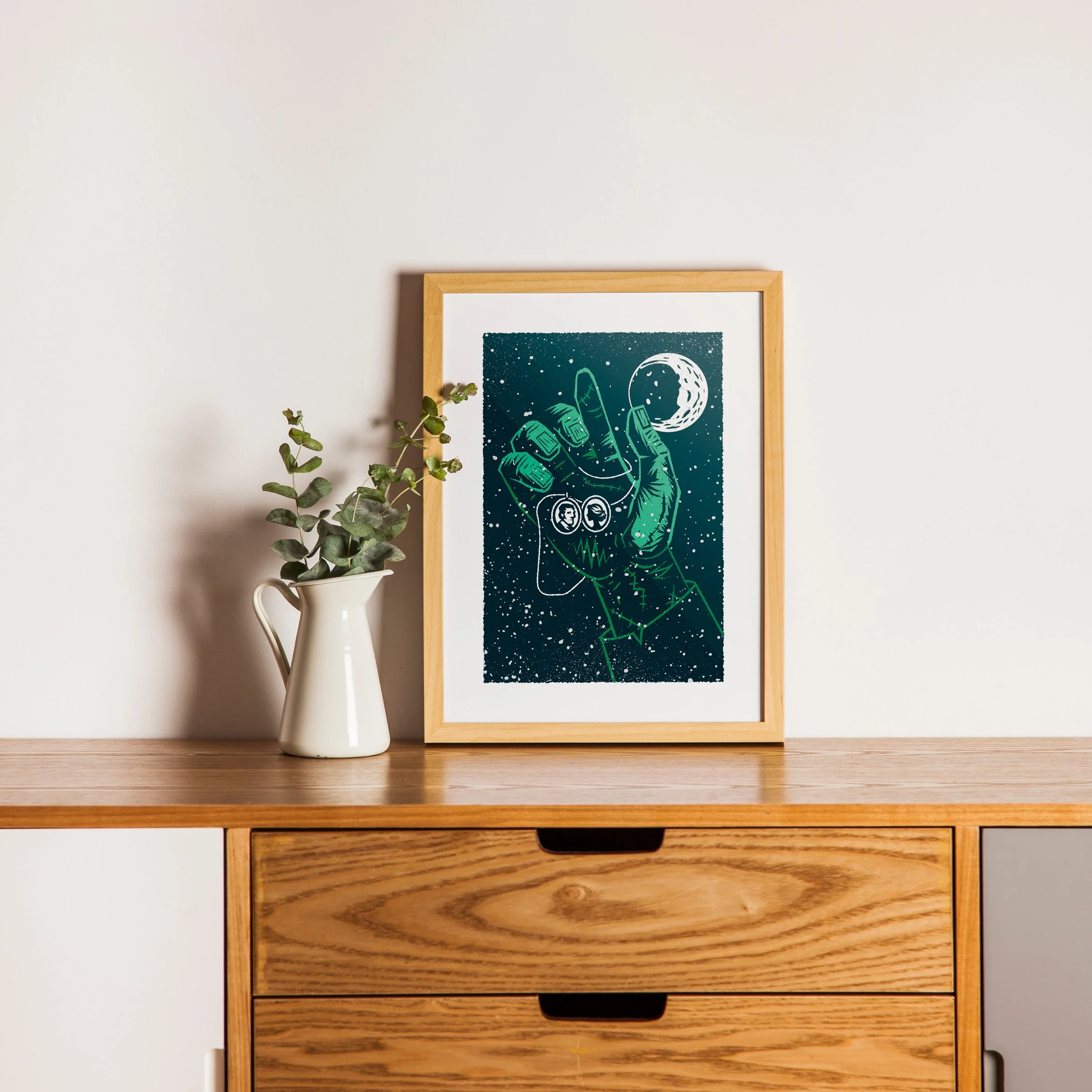 The Spark - Frankenstein Art Print, shown in a oak frame above an oak cabinet. Print supplied unframed.