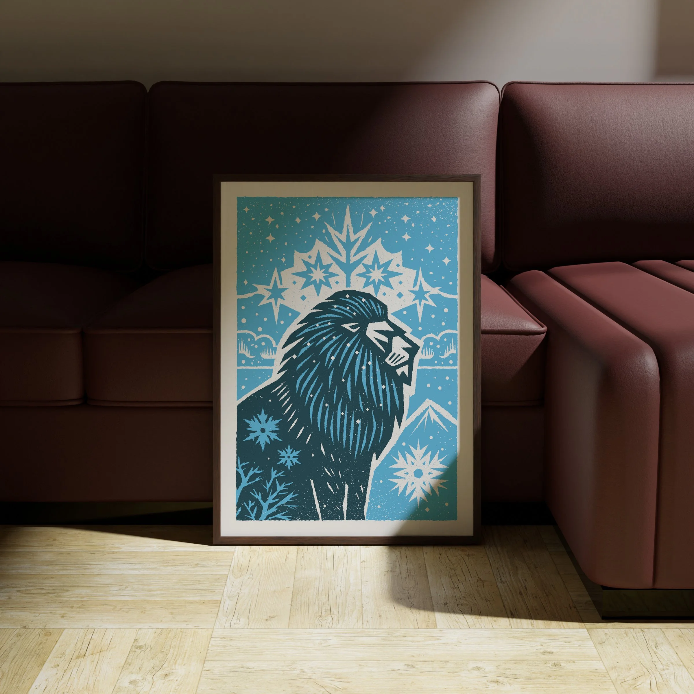 Maneful of Snow - Winter Lion Art Print, shown in a dark frame above a warm sofa. Print supplied unframed.