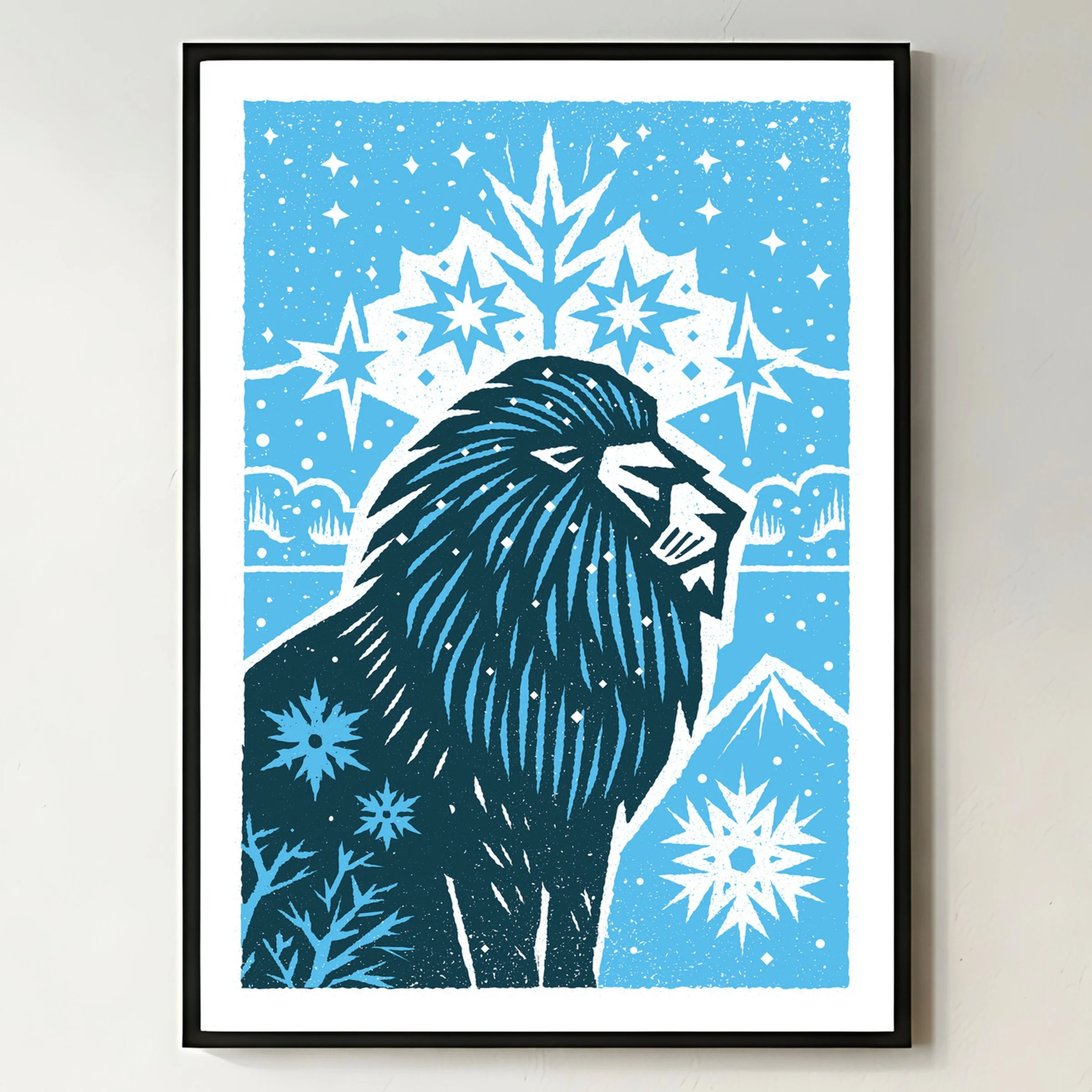 Maneful of Snow - Winter Lion Art Print, shown in a black frame on a bright wall. Print supplied unframed.