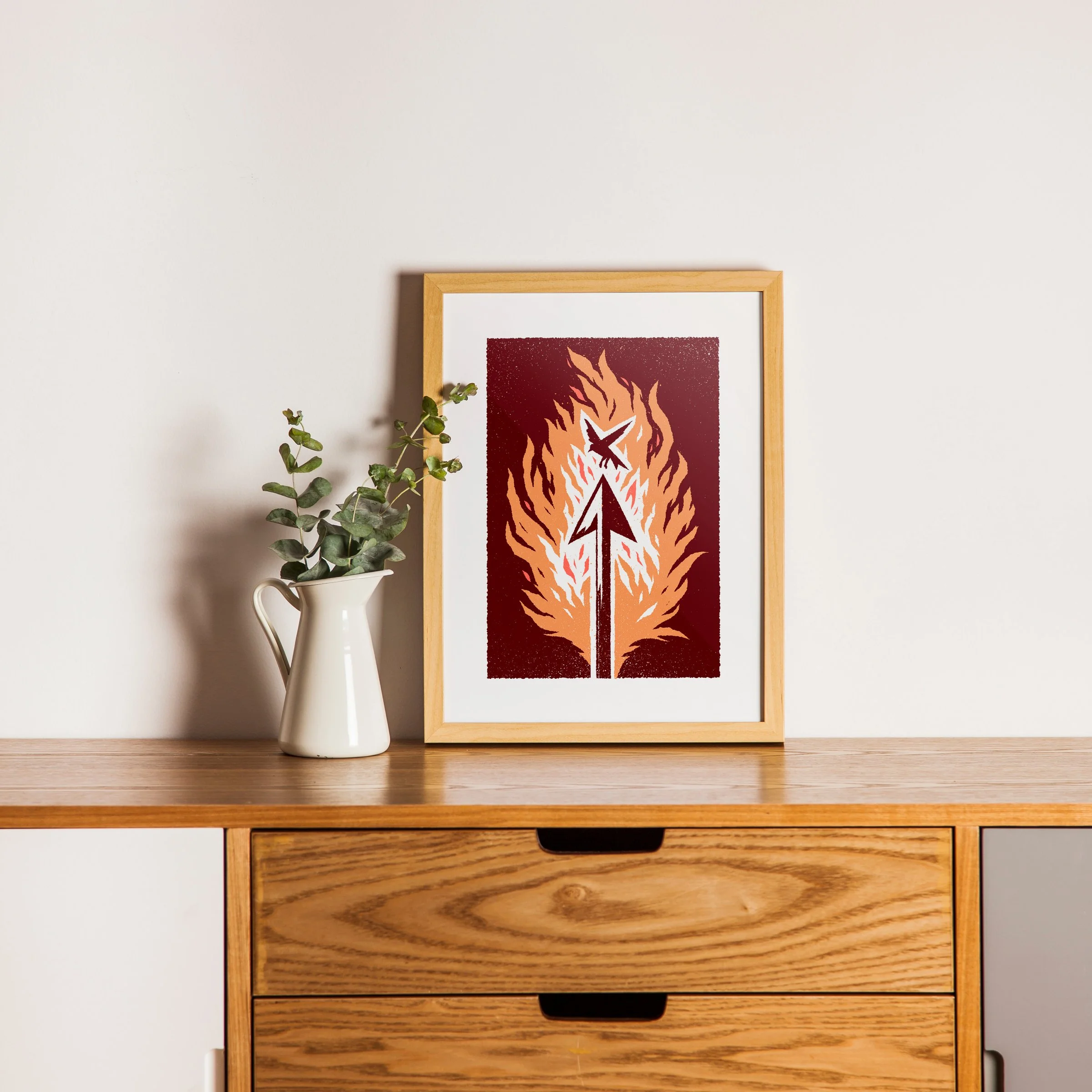 The Shot That Matters - Flaming Arrow Art Print, shown in a oak frame above an oak cabinet. Print supplied unframed.