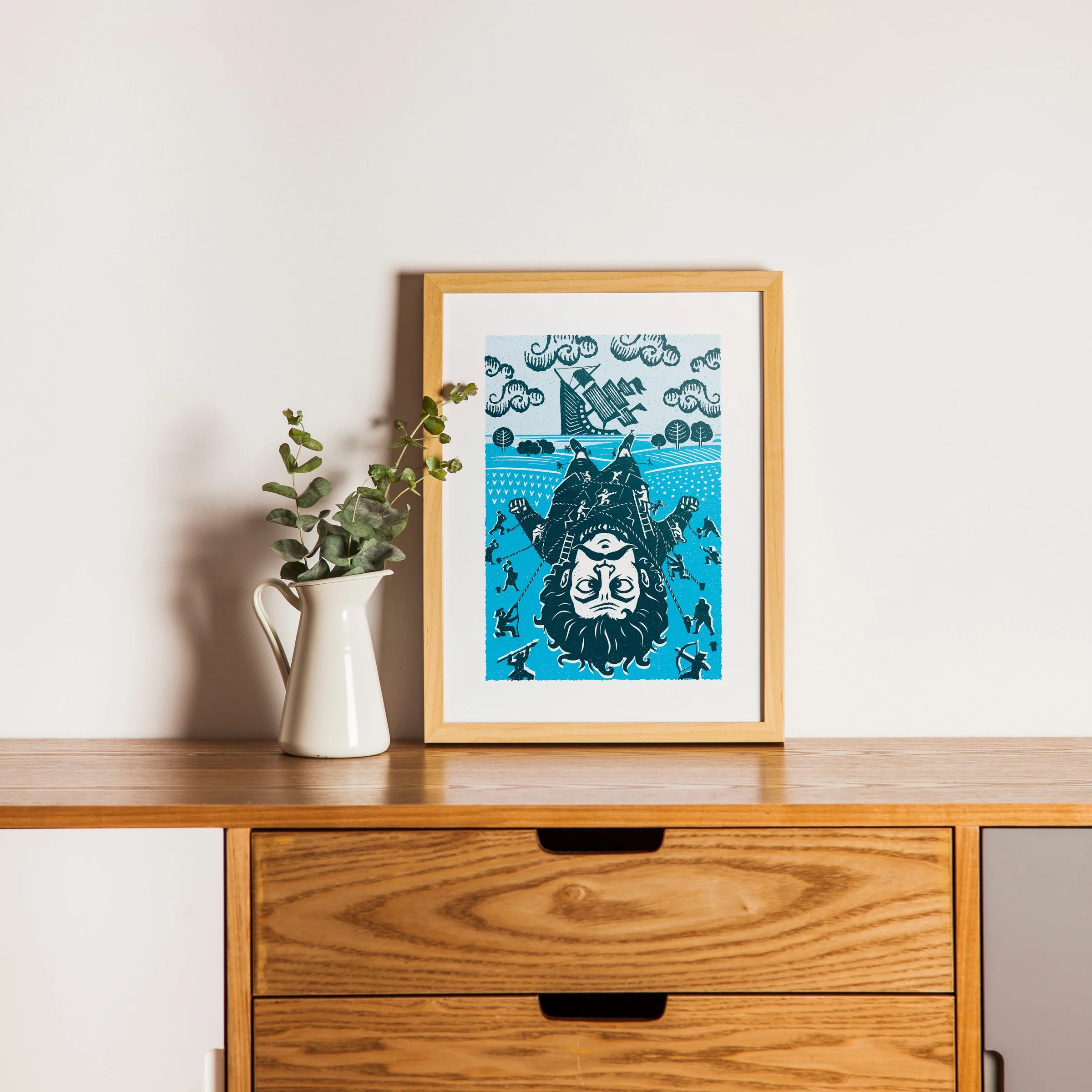 A Matter of Scale - Gulliver Art Print, shown in a oak frame above an oak cabinet. Print supplied unframed.