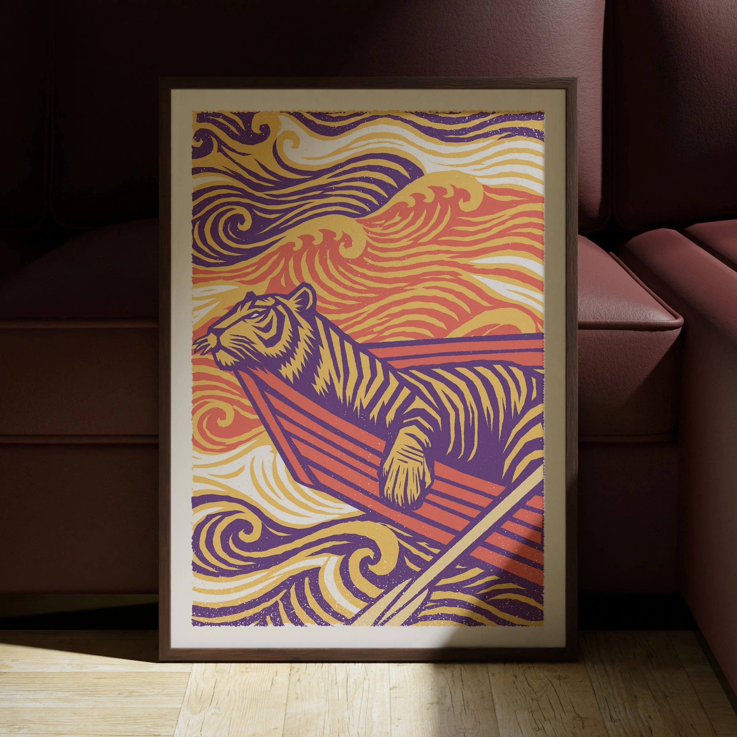 Tiger in a boat illustration by Abby+Owen, shown in a dark frame above a warm sofa. Frame shown for illustration only.