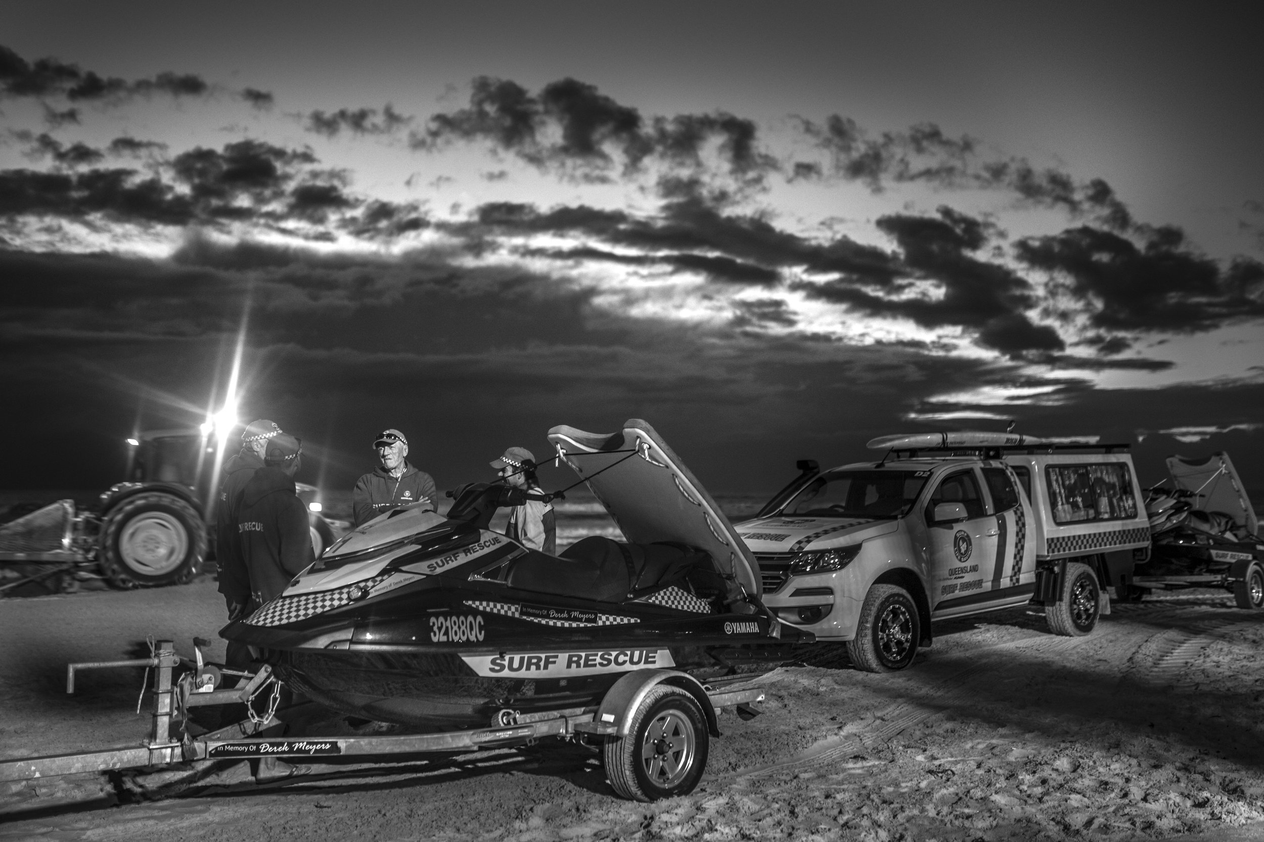 Peter spends about 500 hours a year volunteering for Surf Life Saving Australia, and has no intentions of slowing down. "It's a tough call to put your body and life on the line," Peter explains. The team begin their shift at 4:30am and cover a 16-kilometre stretch of beach from Miami to the Southport Spit until the professional lifeguards begin at 8:00am. They send out two vehicles, patrolling the beach stretch in opposite directions, in order to have a wider eye on the beach swimmers. Whilst the Winter Sun slowly rises over the Cyclone Debbie storm clouds, the Dawn Patrol team meet beside the Jetskis to debrief, assess the situation and check in on each other's health to ensure each team mate is focused.