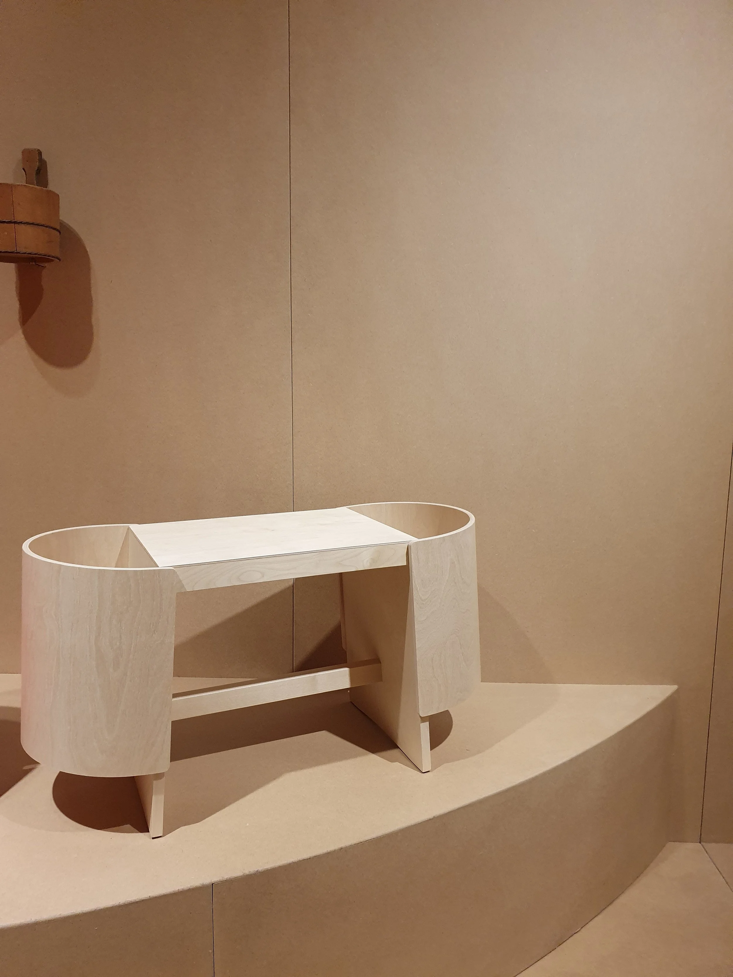 “Inspired by the public bathing cultures of both Finland and Japan, Kiulu Bench typifies the refinement and ability to create new archetypes for which designer Koichi Futatsumata is renowned. Public baths, as both social nexus and cleansing ritual, are deeply embedded in the cultural landscapes of both Finland and Japan, and this connection is taken as the designer’s starting point. A cylindrically shaped bucket, Kiulu in Finnish, is traditionally used in public baths of both countries and stands at the origin of Futatsumata’s bench design. Kiulu Bench serves several functions - as seat and basket, offering storage for items such as towels and cosmetics, magazines or toys. Embodying Futatsumata’s concern with material and eye for detail, Kiulu Bench can find its application in the dry surroundings of the bath/spa/wellness area and beyond.