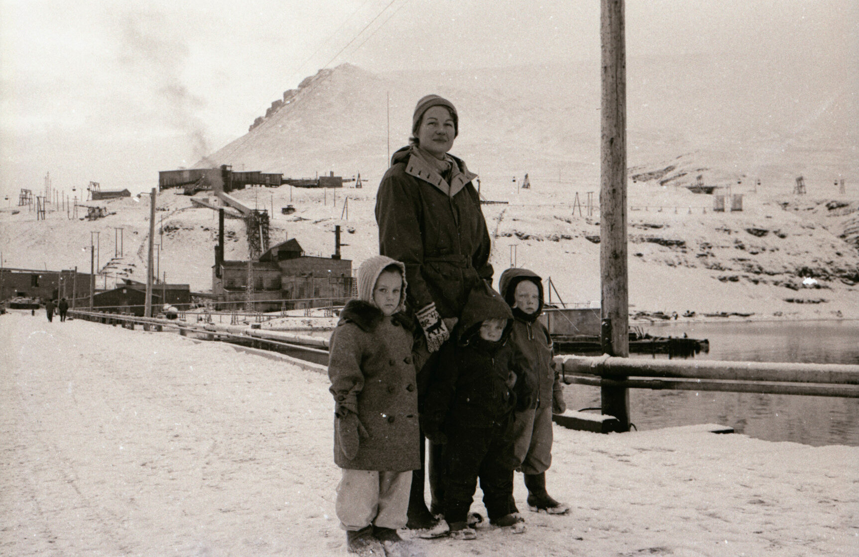 Mormor med barn ved havnen. Kraftstasjonen i bakgrunnen. 