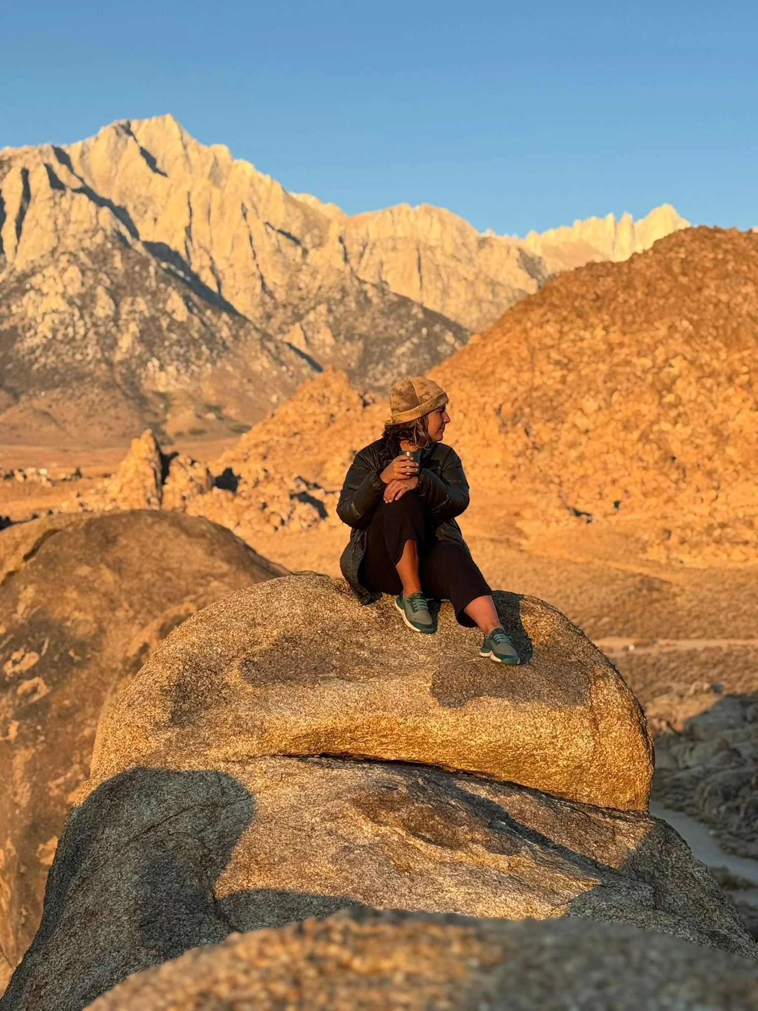Woman sitting on mountain at sunrise in Alabama Hills, CA
