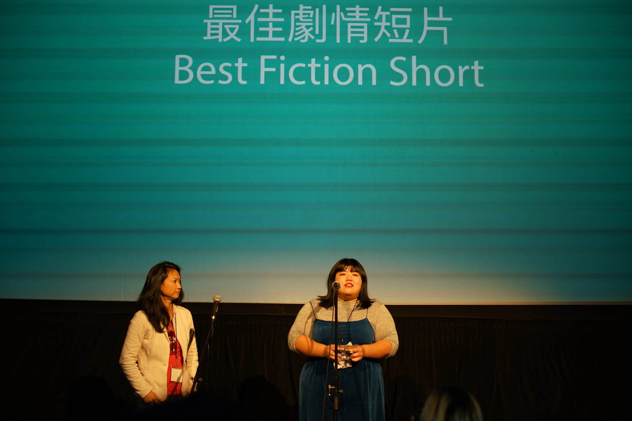 终审评委Monica Chuo为最佳剧情短片颁奖(左)策展组影人经理杜佳忆代表赵祖祥导演导演宣读获奖感(右)