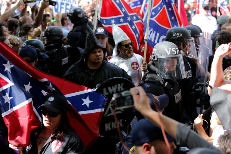 On Saturday, riot police in Charlottesville, Va., protected members of the Ku Klux Klan from counterprotesters as they rallied to oppose a proposal to remove a statue of Robert E. Lee from a city park.CreditJonathan Ernst/Reuters