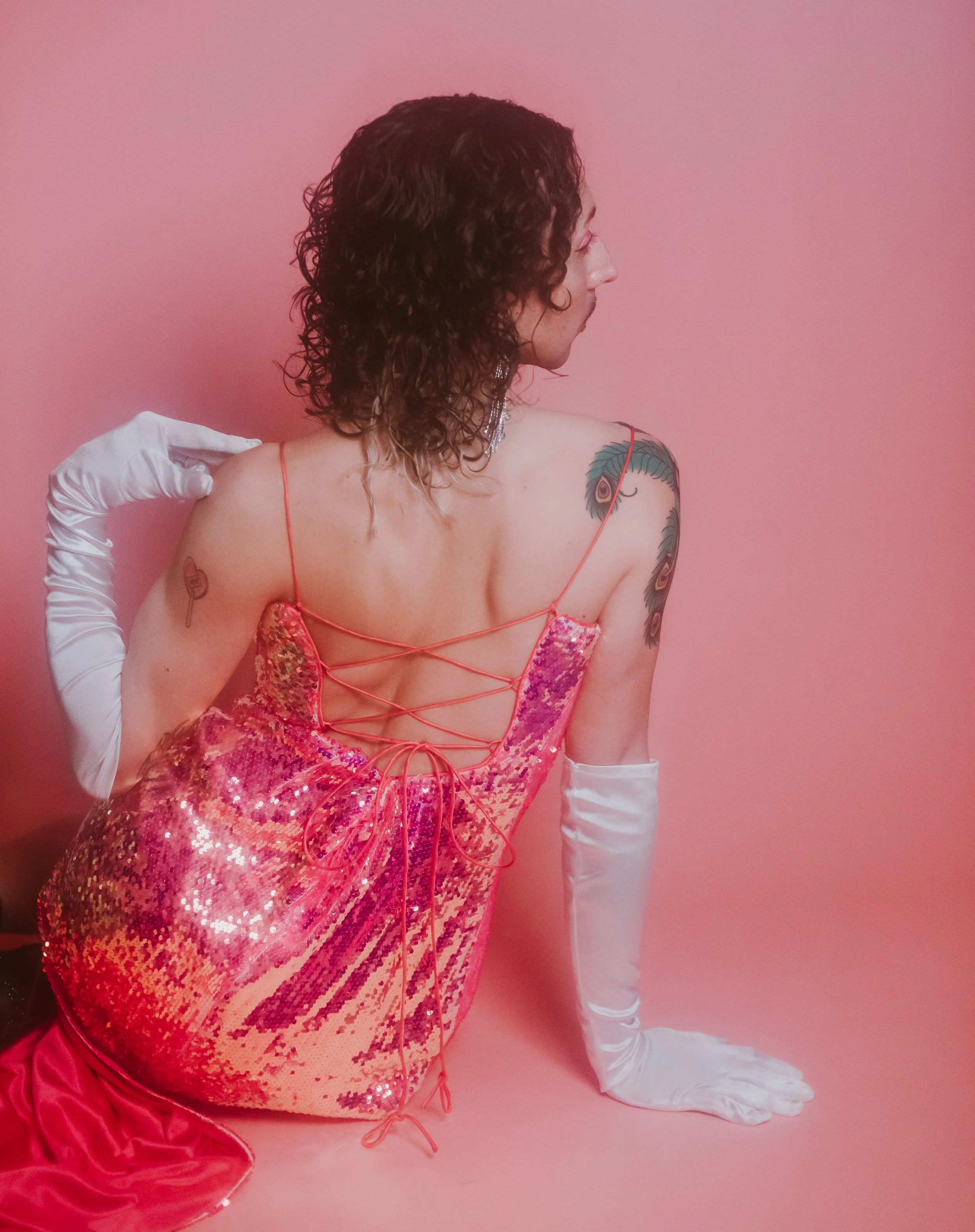 denton burlesque performer prince axle posing at flesh and flora photography studios in a pink sequin dress.
