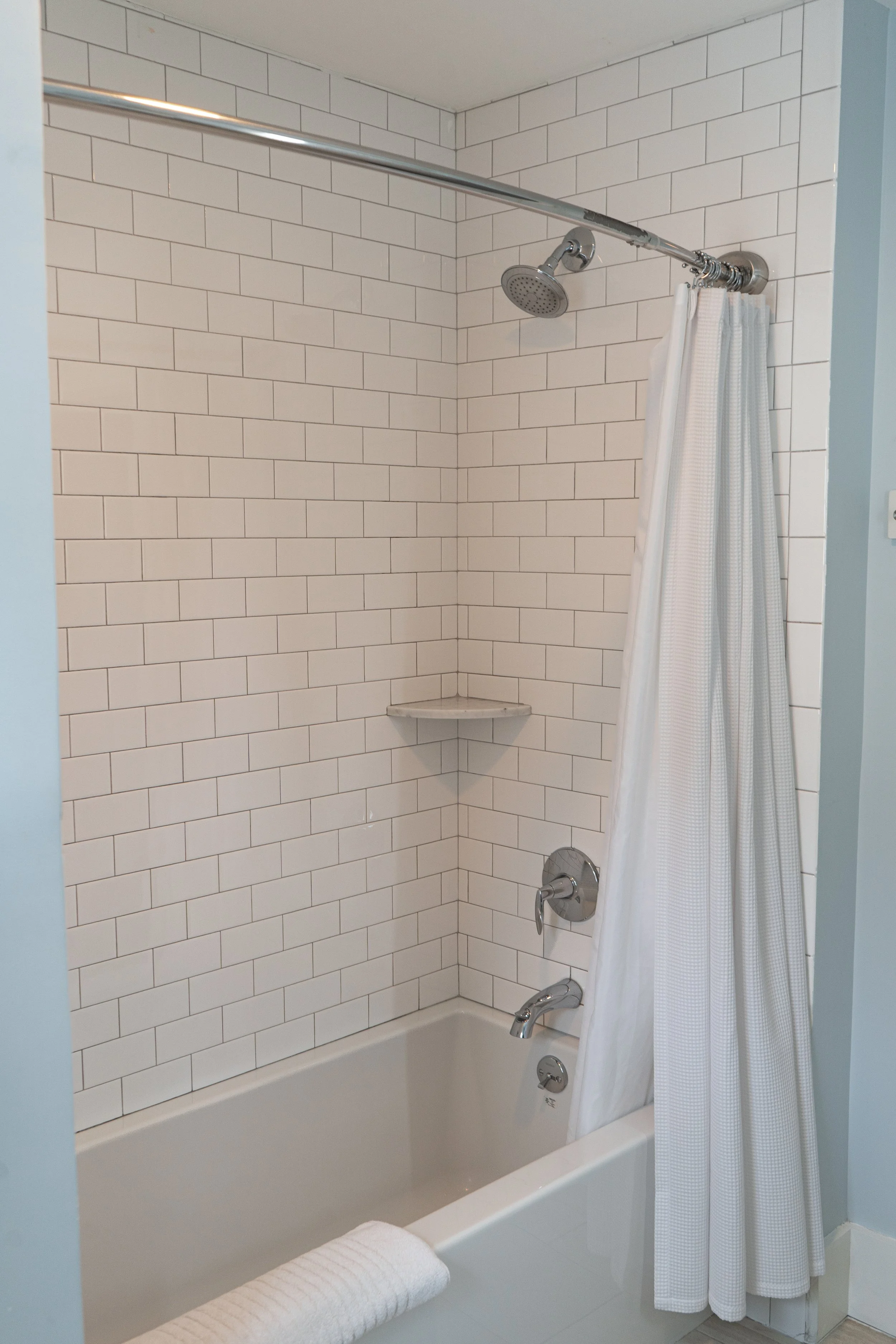 Bathroom shower in Room 7 at The Sailmaker’s House with white subway tile and curved shower rod
