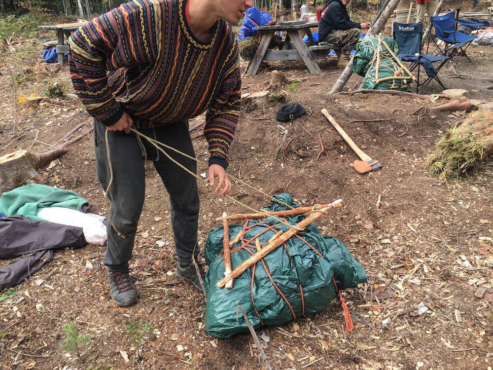 Zander ties a bundle of gear to his packframe.