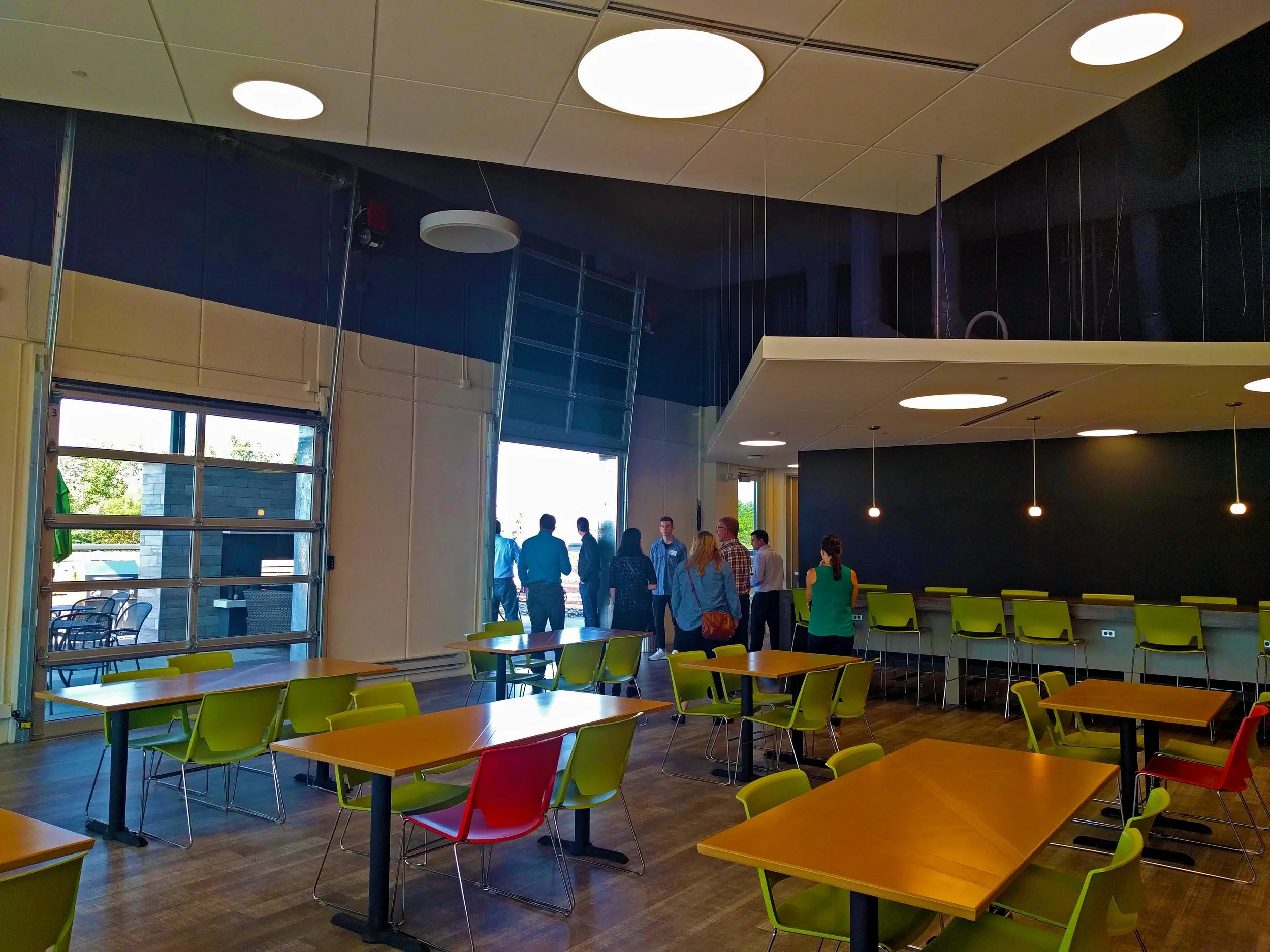 Their cafeteria doubles as a meeting area and as a more relaxed area for employees to work. The space spills out onto the outdoor patio and fireplace through large overhead doors. 