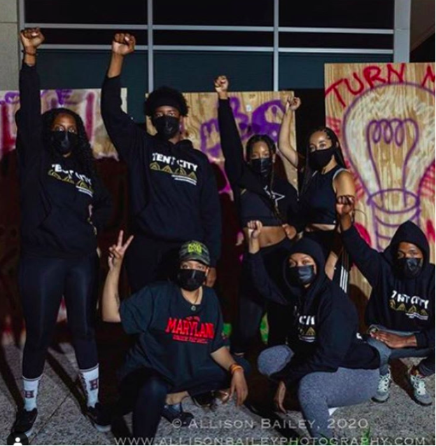 Saba Tshibaka, bottom left, pictured with Aniyah Vines, bottom middle, and a group of fellow protestors at the Tent City occupation on Oct. 24. (Allison Bailey/Allison Bailey Photography)