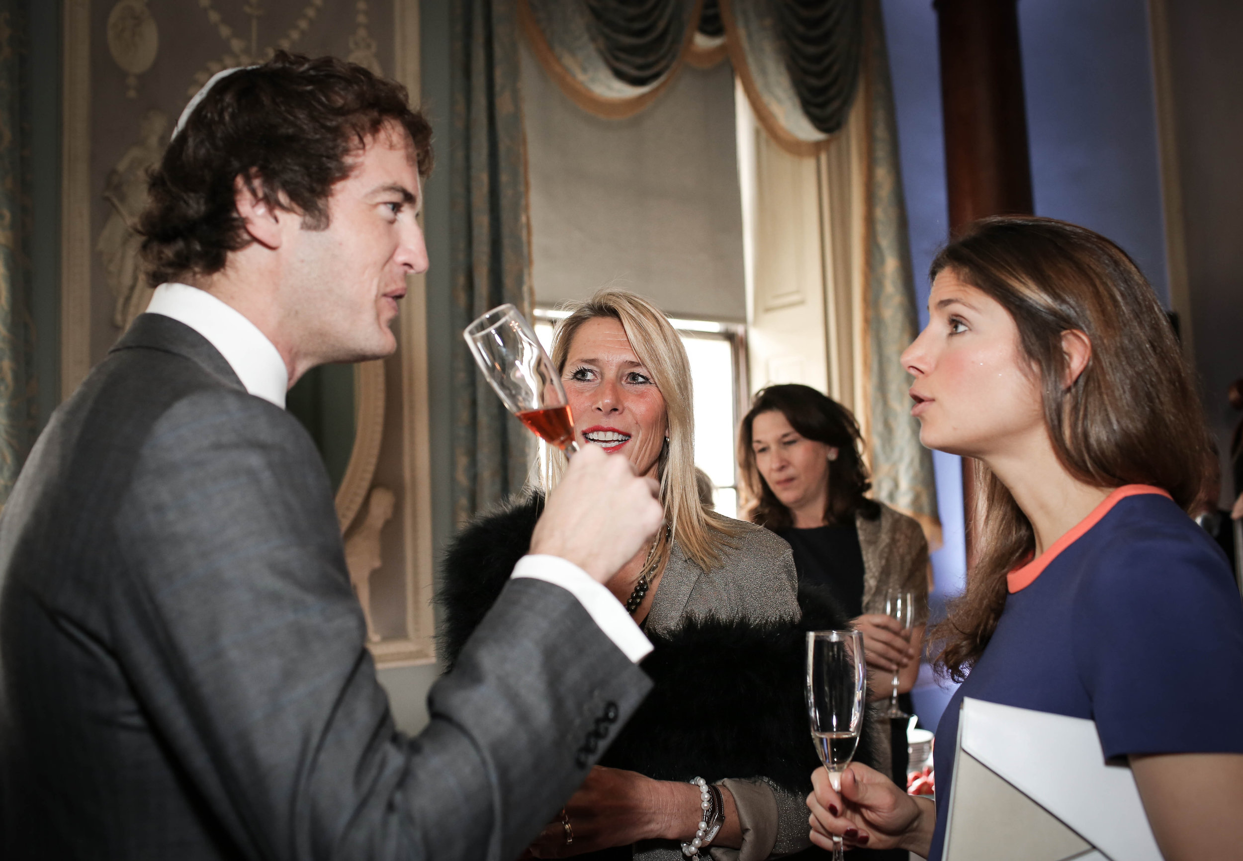 People at a formal event holding glasses, engaged in conversation.