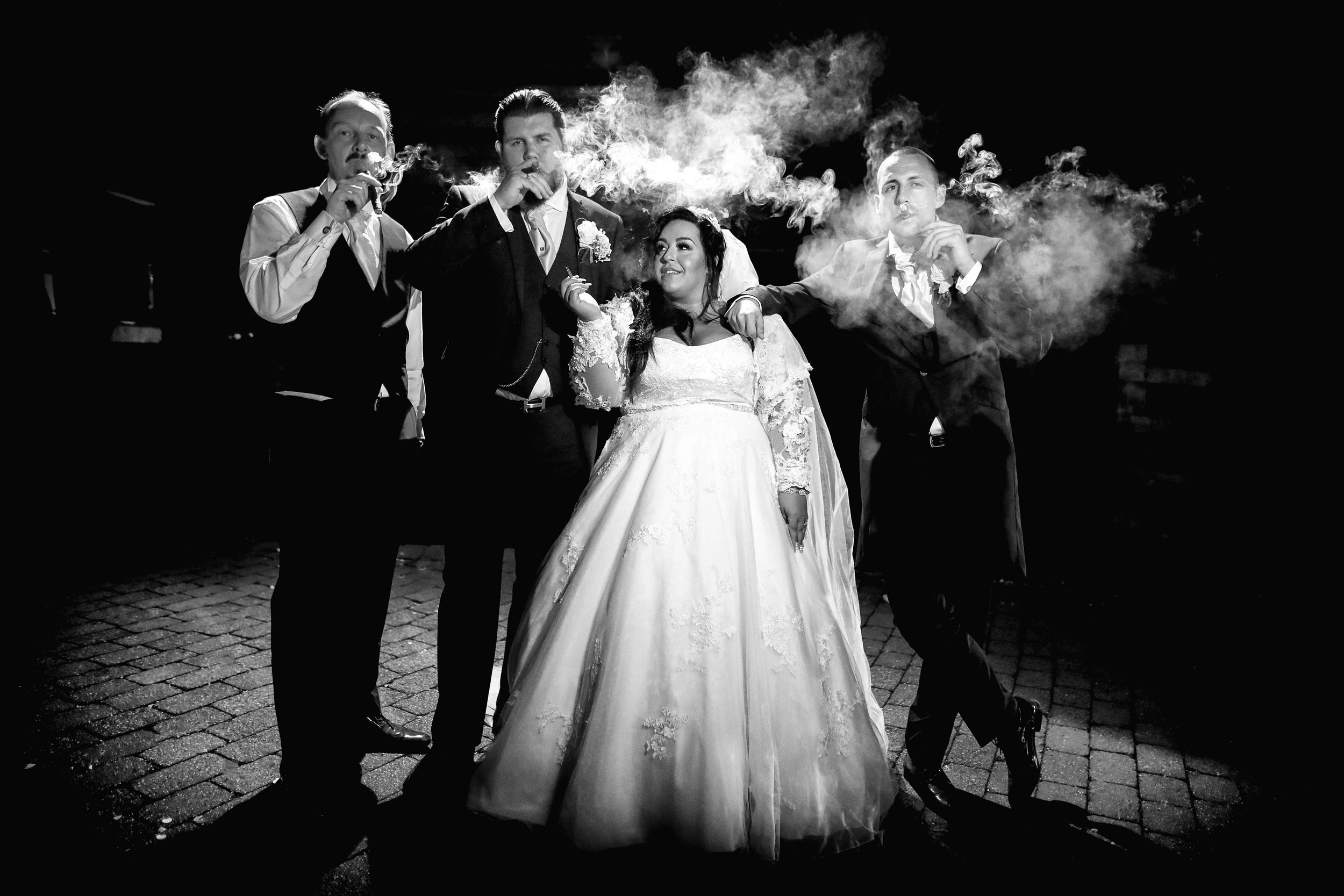 Bride and three men in suits smoking cigars, nighttime, black and white photo.