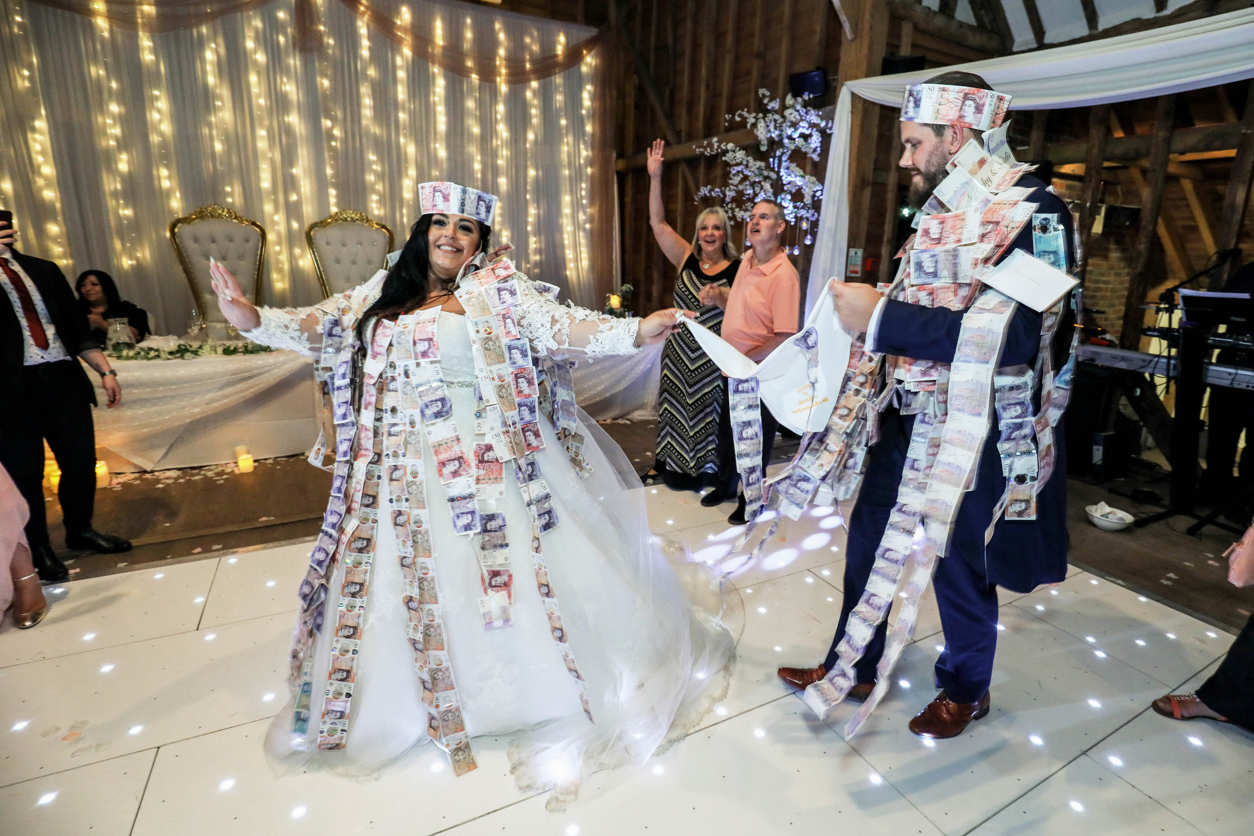Bride and groom covered in money at a wedding celebration indoors.