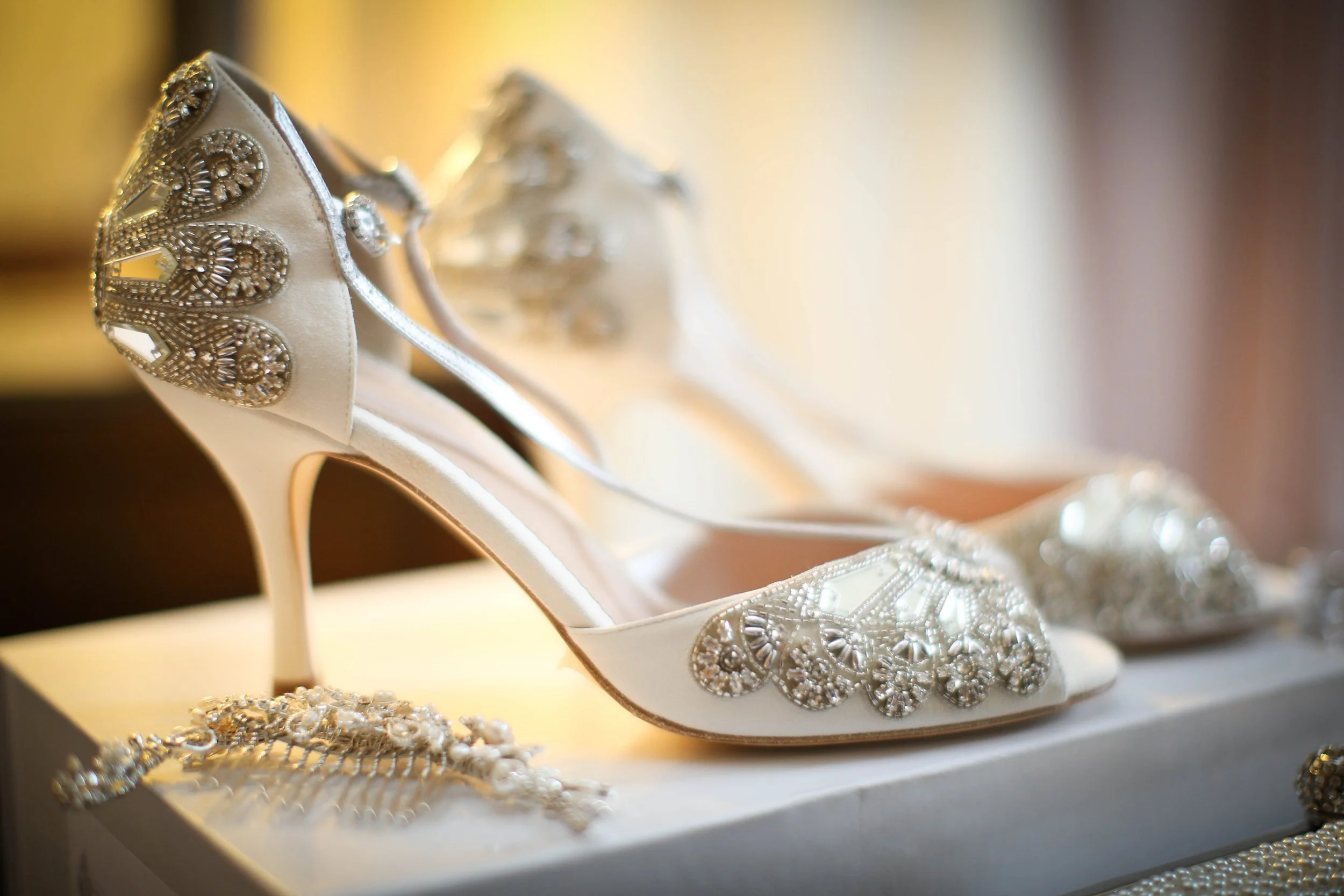 Elegant white high heel shoes with intricate beadwork and embellishments.