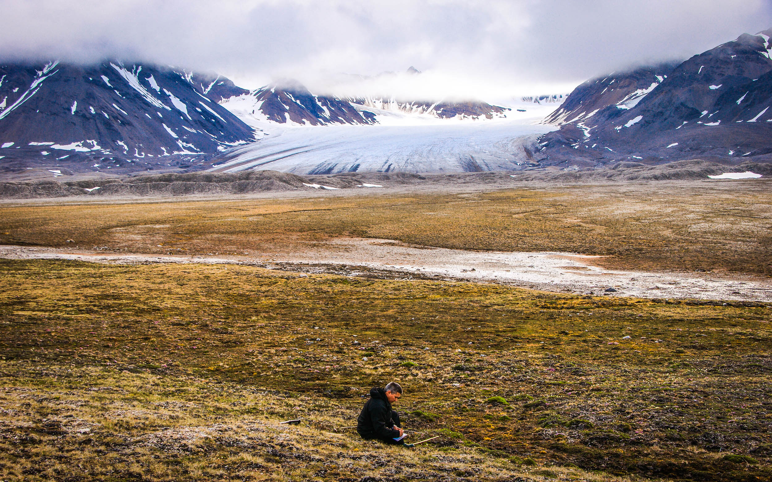 Jarle W. Bjerke doing research work with Vestre Brøggerbreen glacier in the background.  JONAA©Trond Johnsen