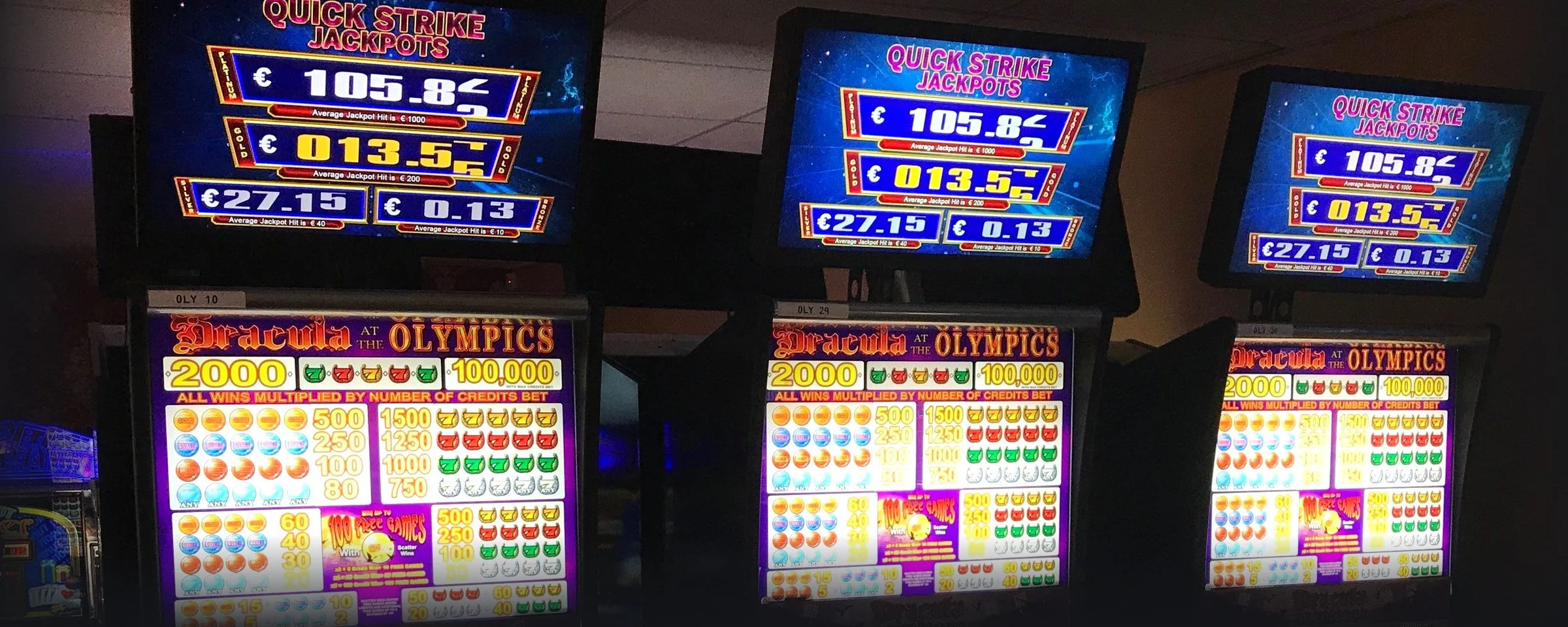 Quick Strike Jackpots signage showing live meters above a bank of Dracula at the Olympics cabinets on a casino floor