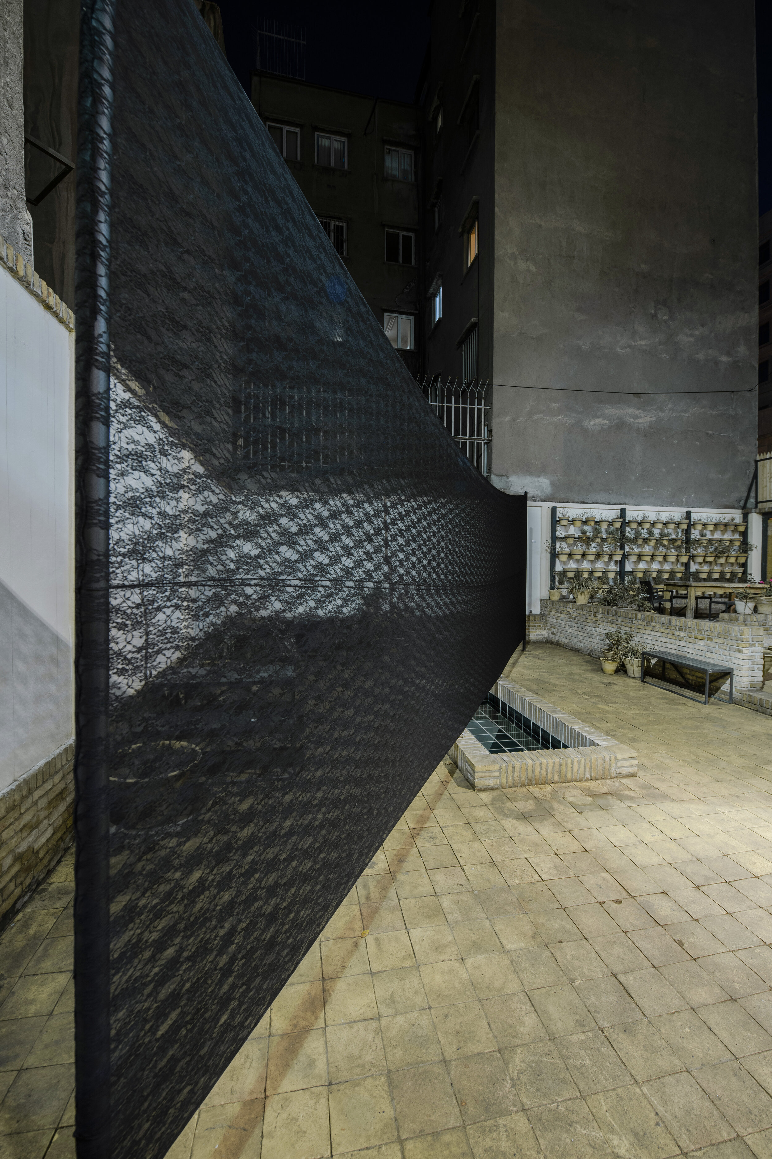  Untitled (Put to Work) Metal poles, lace, cable 360 x 900 x 6 cm (بدون عنوان (خرج کار  *a 9 meters long and 3.5 meters high screen of lace mesh diagonally divides the courtyard of the gallery. Hence, upon entering into the courtyard, the visitors sh