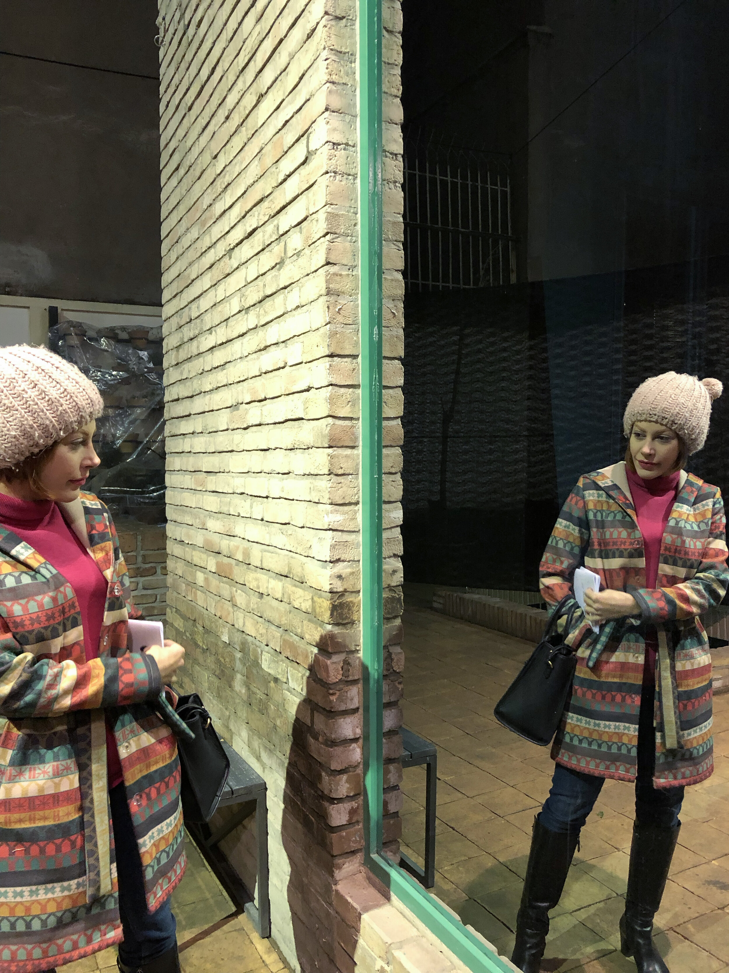   *A visitor to the courtyard of the gallery checking on herself in the mirror side of the one-way mirror, while being possibly gazed at by some visitors to the communal room toward which the window side of the one-way mirror faces.  