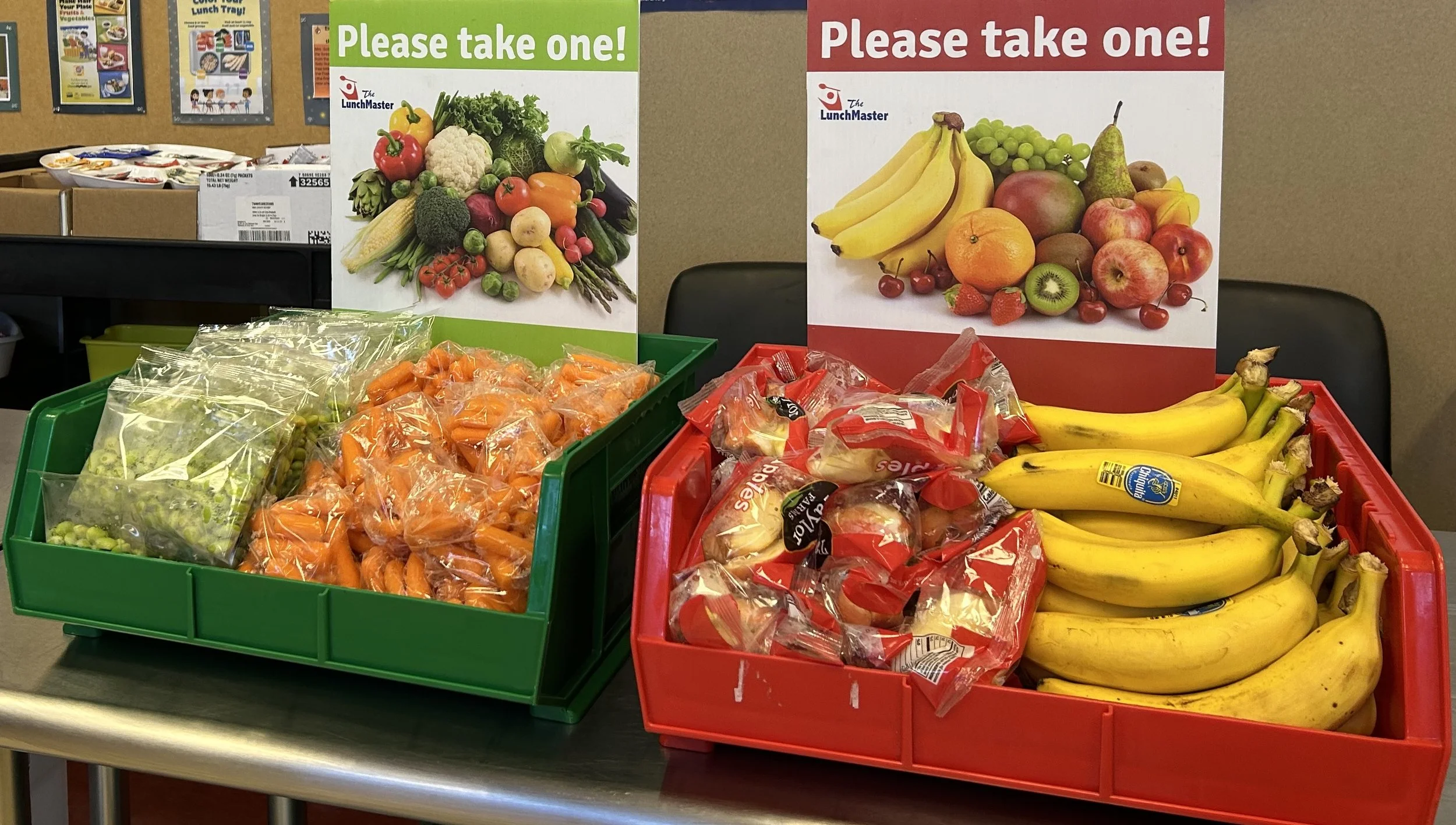 Edamame, carrots, apple slices and bananas in lunch bins