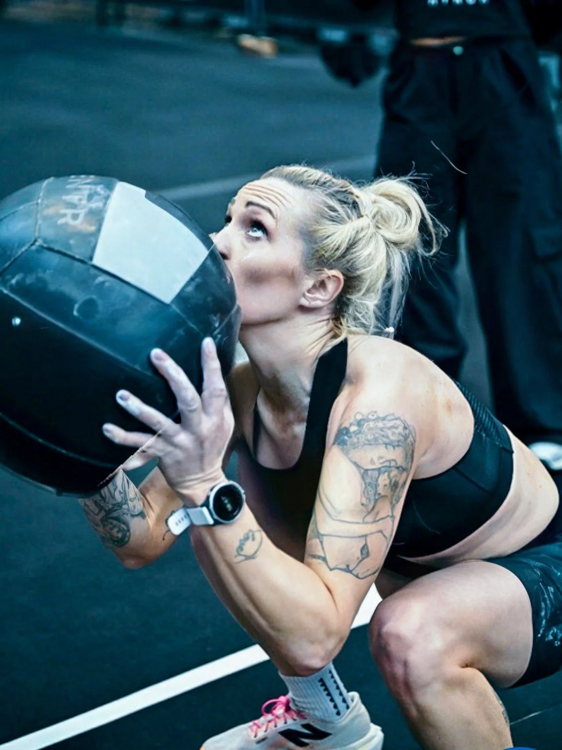 Nat Lawrence holding a wall ball during a HYROX workout station.
