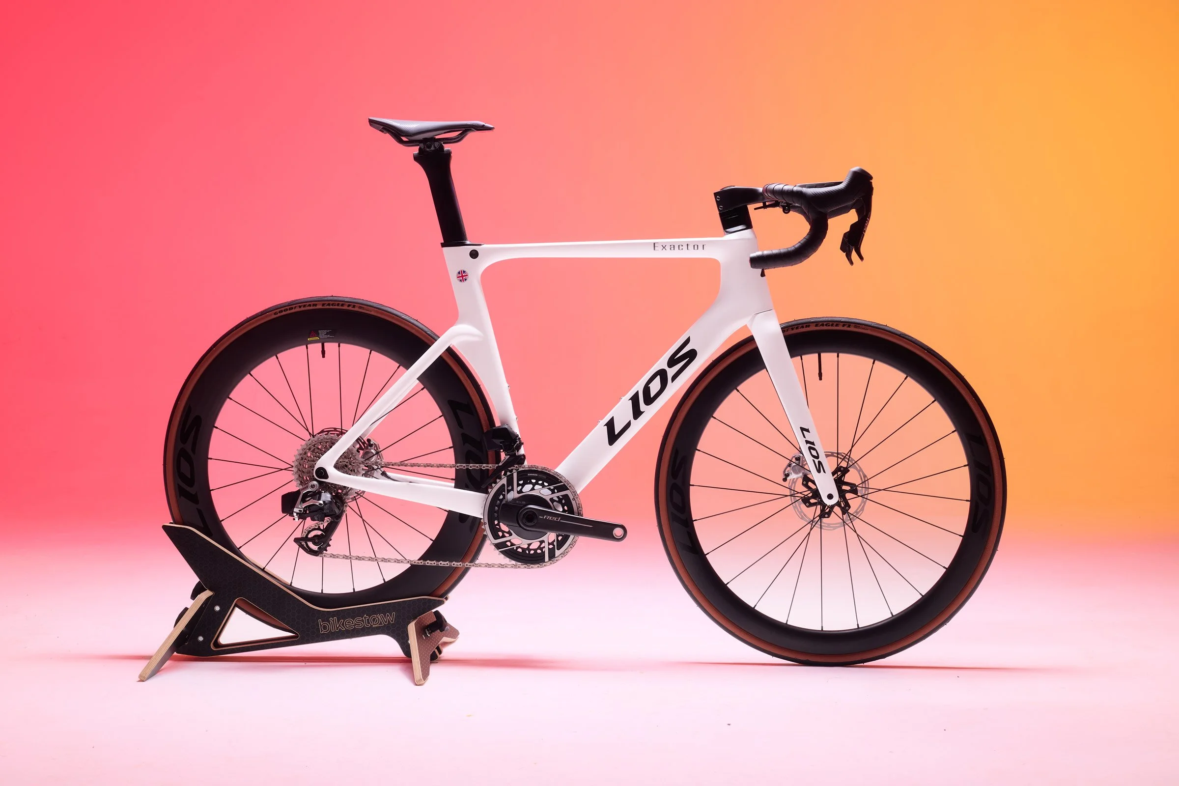 LIOS Exactor aero road bike photographed in a studio with orange and pink lighting.