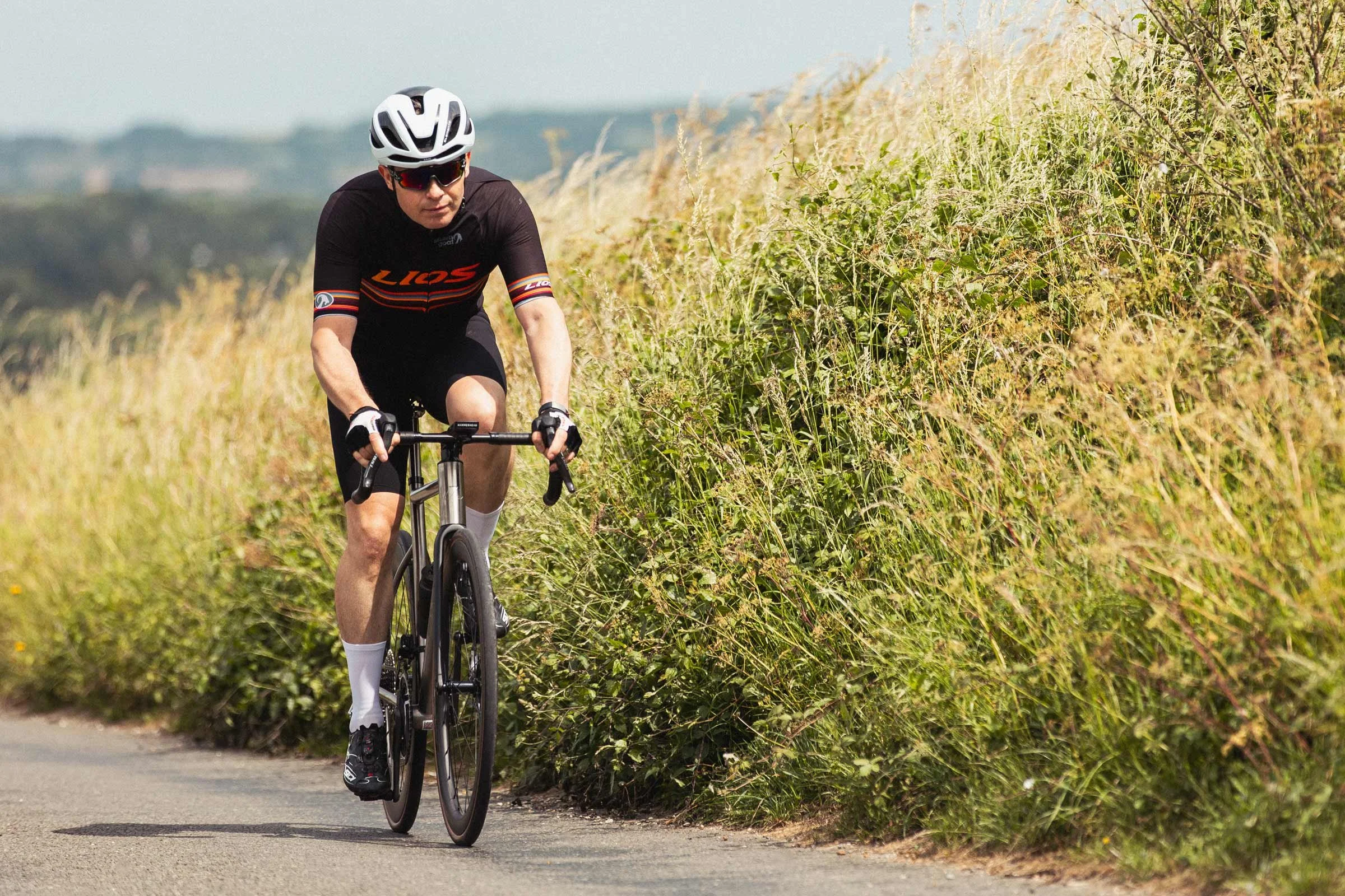 LIOS Ambassador Dave Spink cycling along a country lane on his LIOS Titanium road bike looking very relaxed.