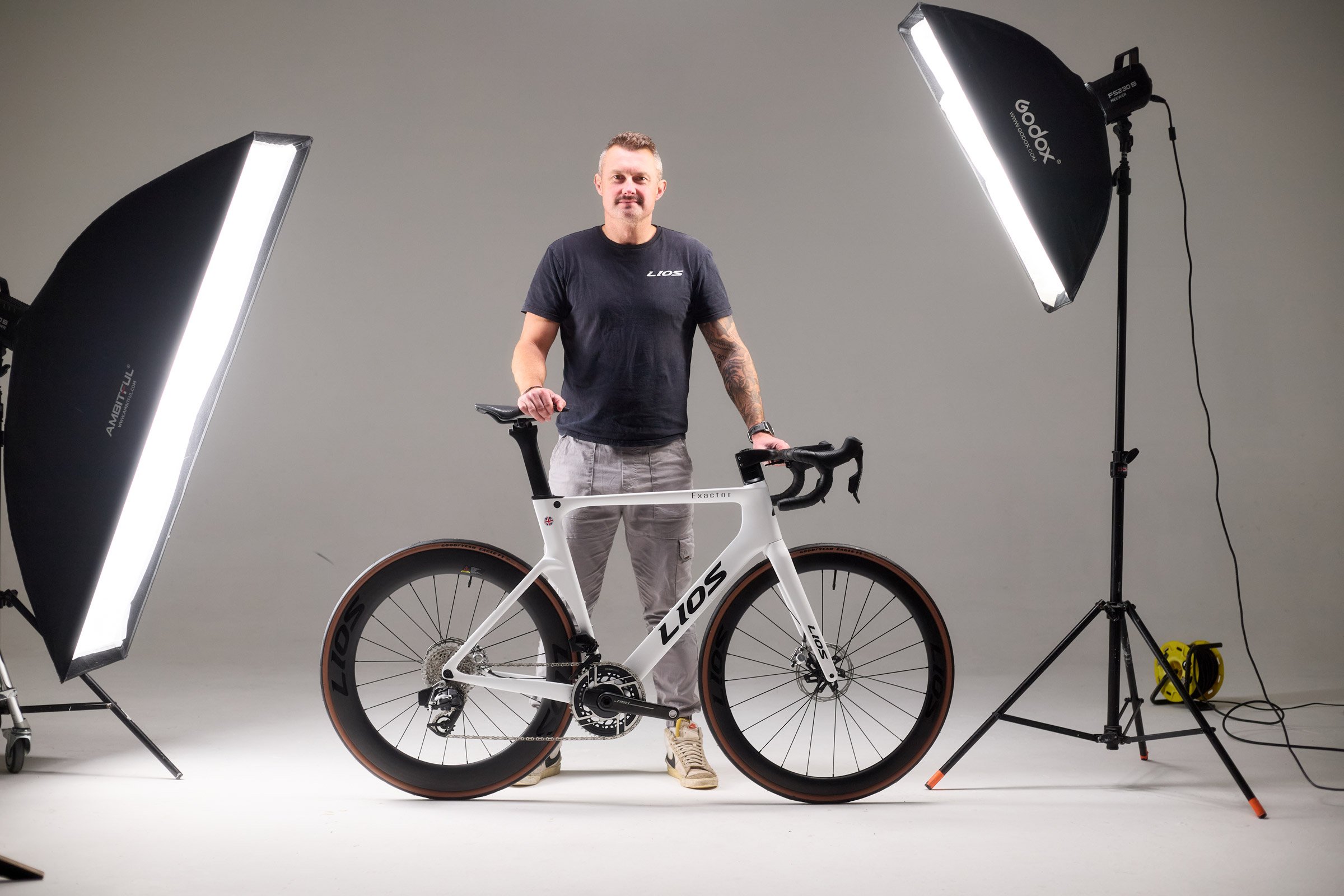 Steve McCulley, founder of LIOS Bikes, stood in a photo studio with a LIOS Exactor aero road bike.