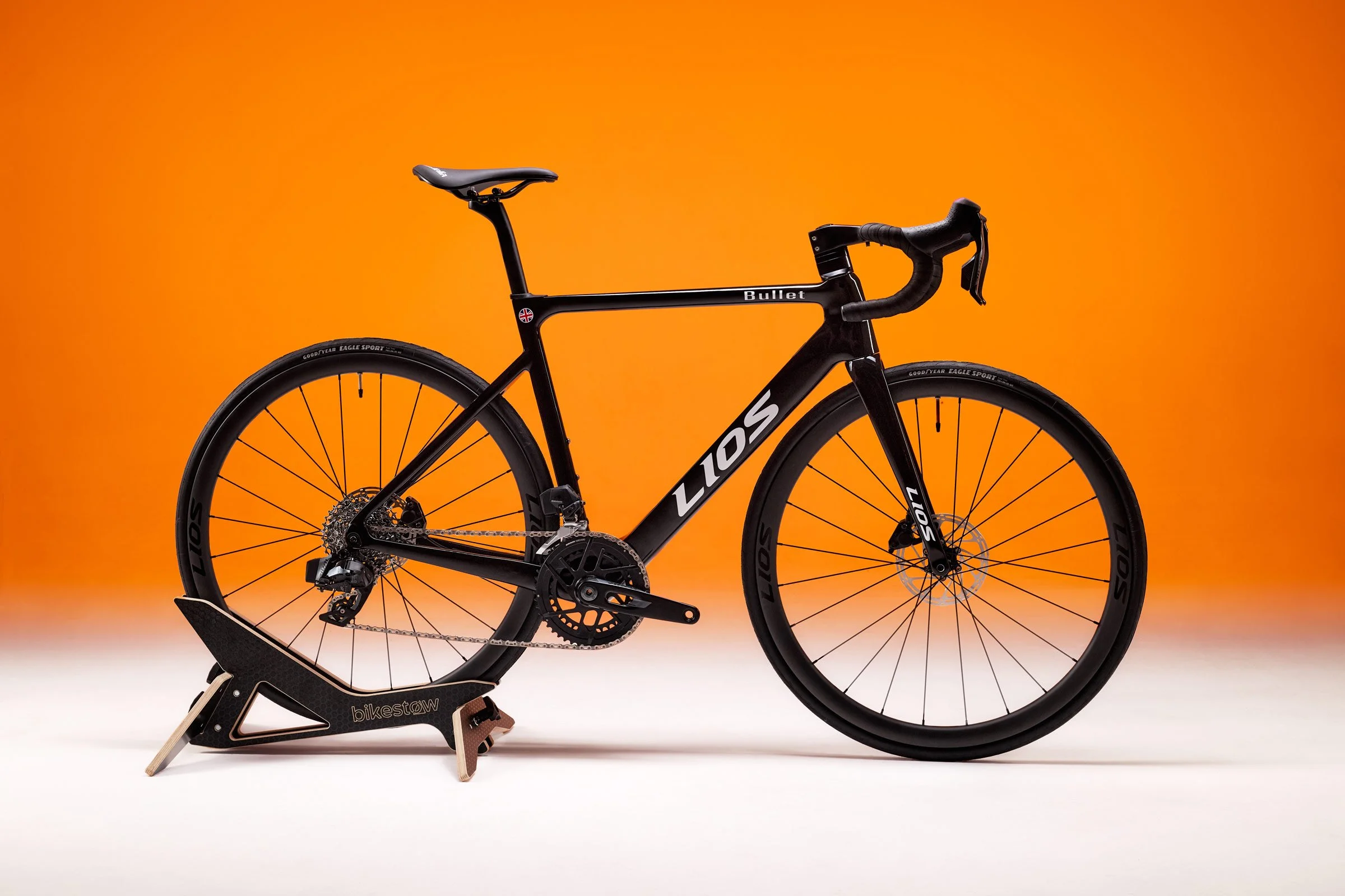 Studio photograph of a Midnight Black LIOS Bullet 5.56 endurance road bike, which has been backlit with orange.