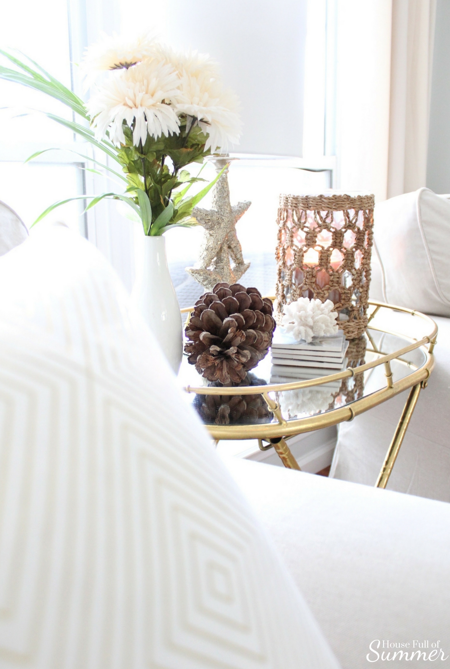 House Full of Summer: Fall Home Tour Blog Hop - Cozy, Coastal, Chic Living Room fall decorating ideas. Neutral interior, living room decor, gold bamboo folding table, mirrored side table, throw pillow covers, faux fall florals, living room ideas, sitting room, wood floors, table styling, pine cones, gold accents