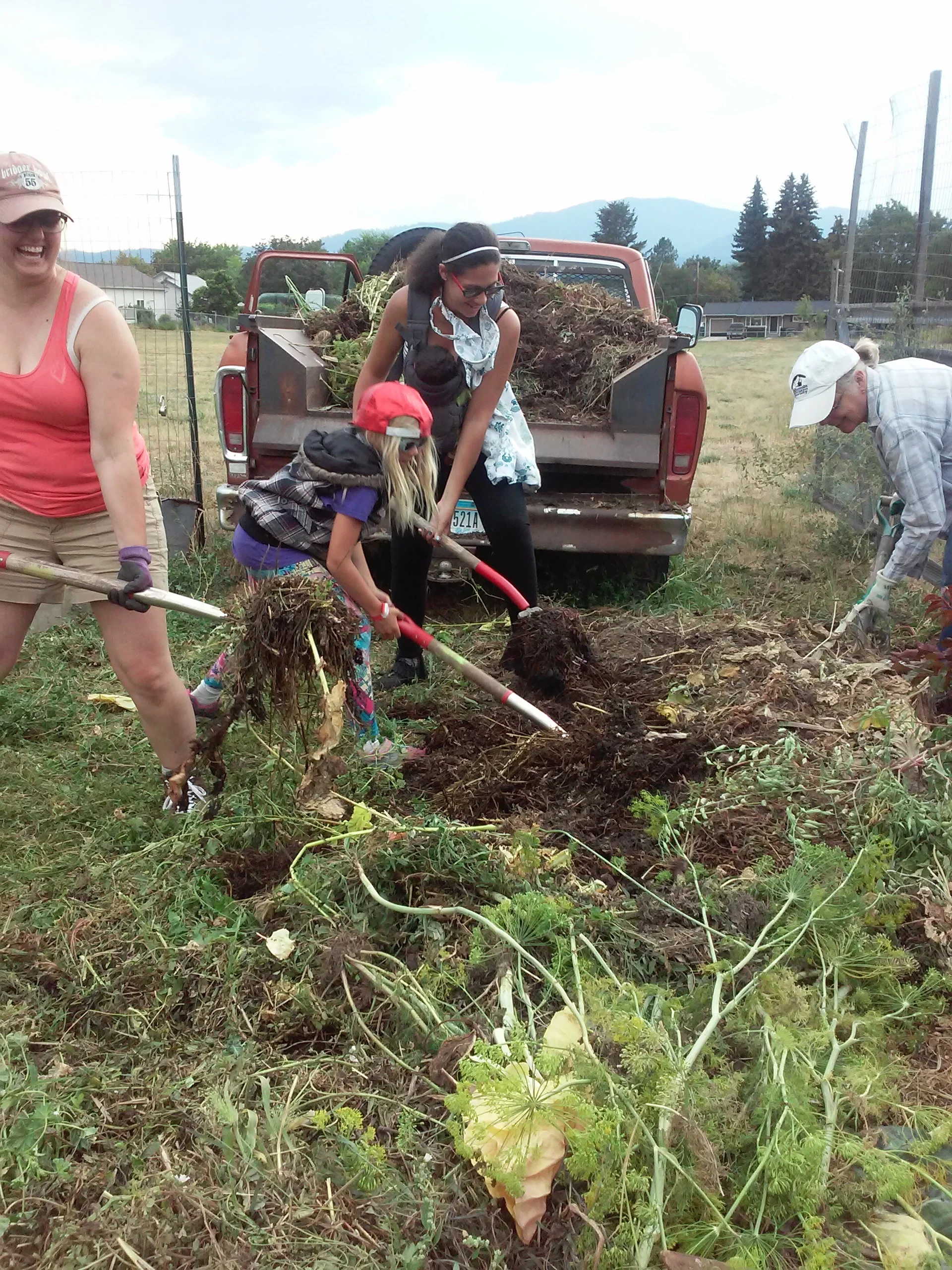 Meadow Hill leadership committee members and gardeners pitch in together to move the giant weed pile to another community garden with more space where it will eventually turn into compost.