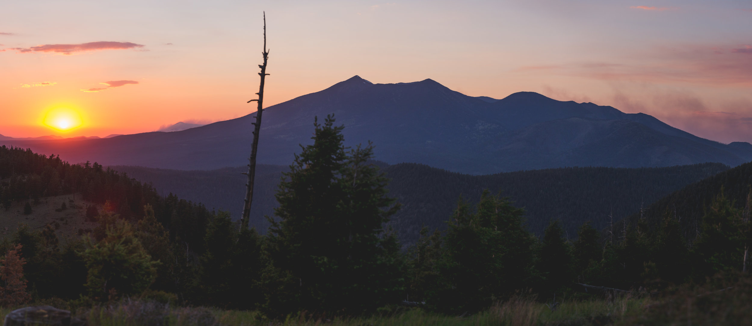 Smoke from wildfires brings a red-orange haze over the peaks, as viewed from atop Mount Elden