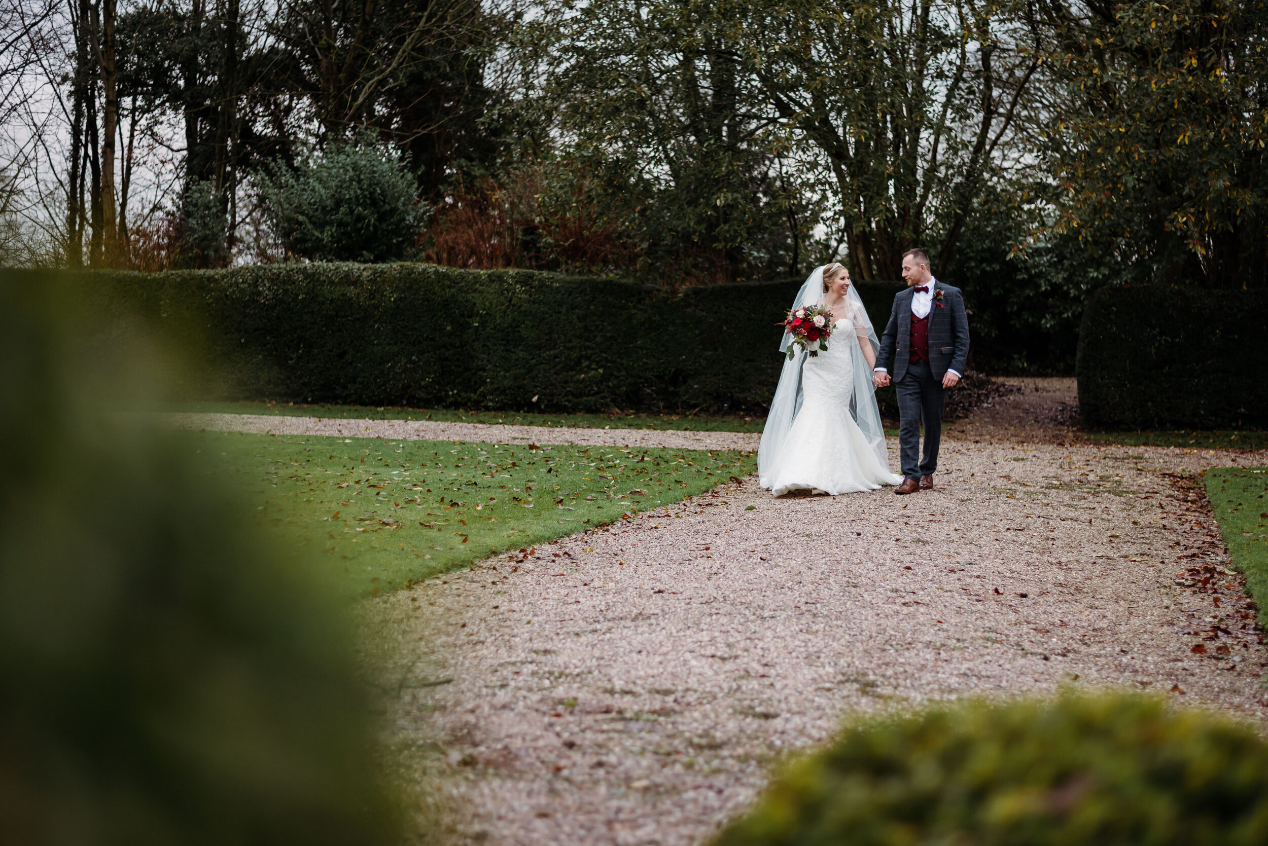 Winter bride and groom walking through the grounds at Eaves Hall
