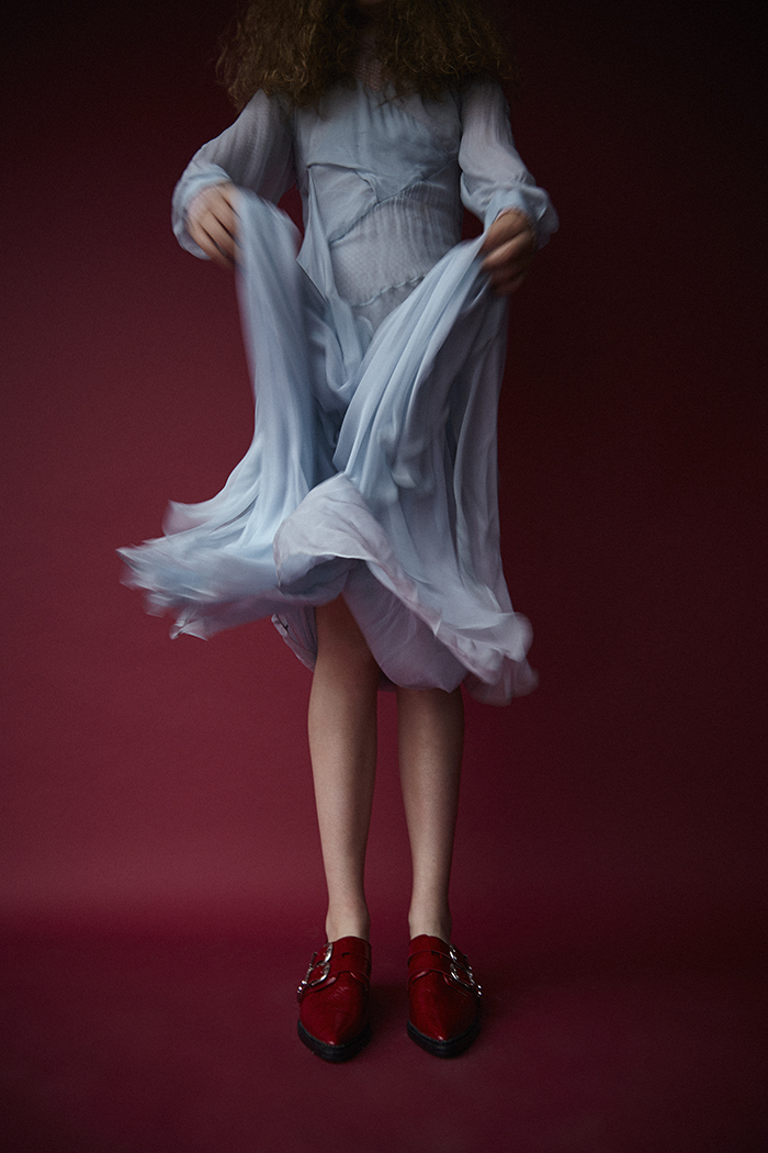 Erin wears powder blue sheer dress by Vionnet and red flat shoes with buckles by Toga