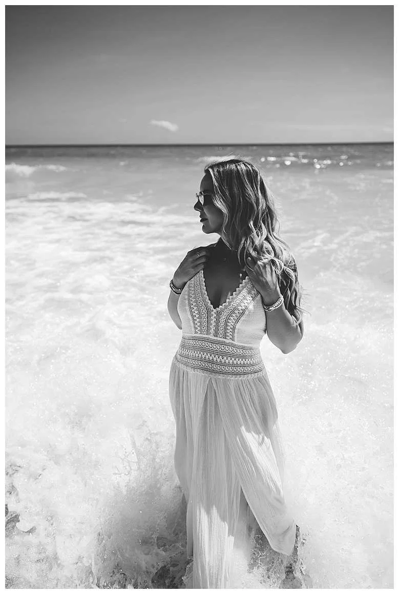 black and white image of a woman in a white dress on the beach